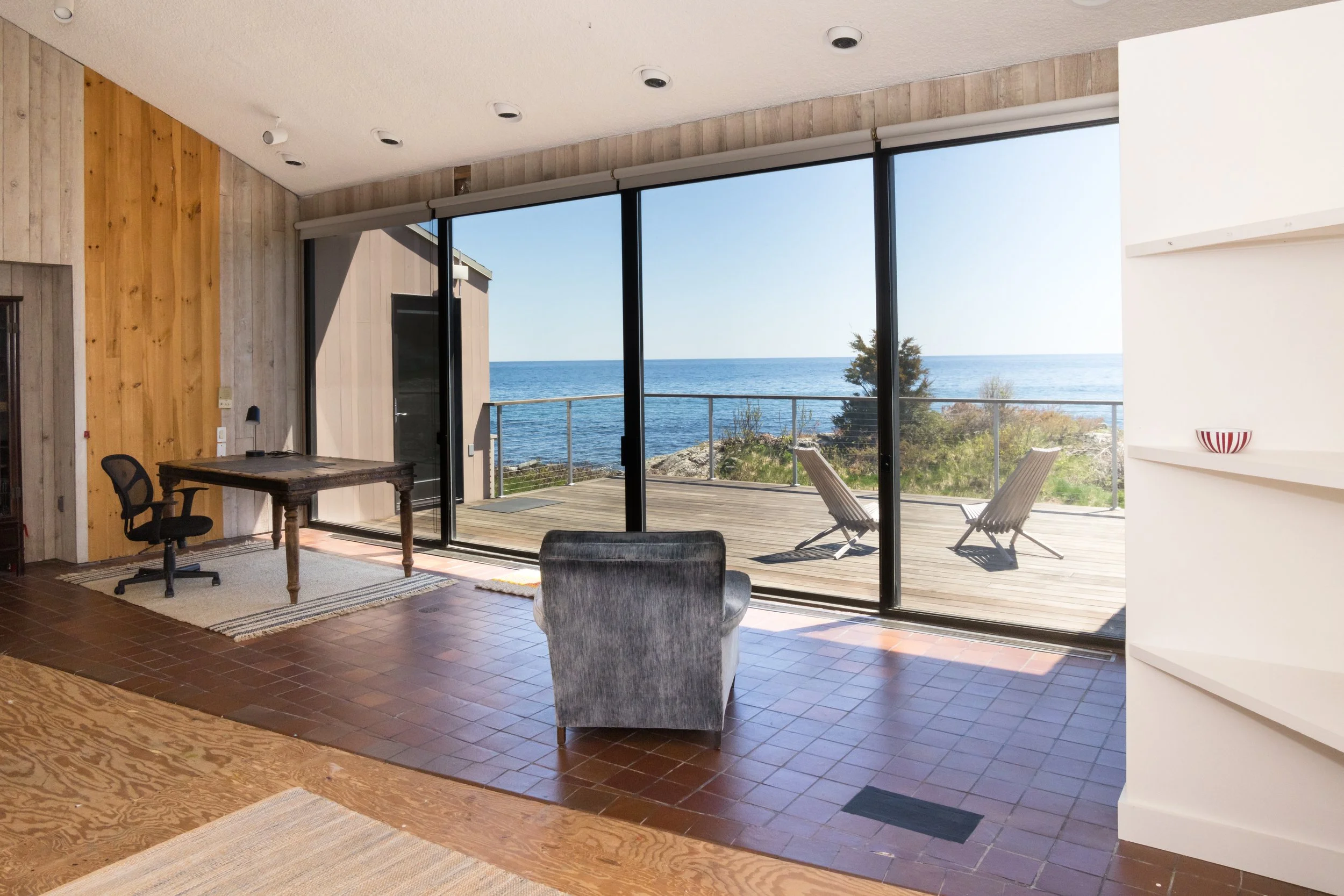 Interior of a modern room with large glass doors overlooking a deck and ocean view