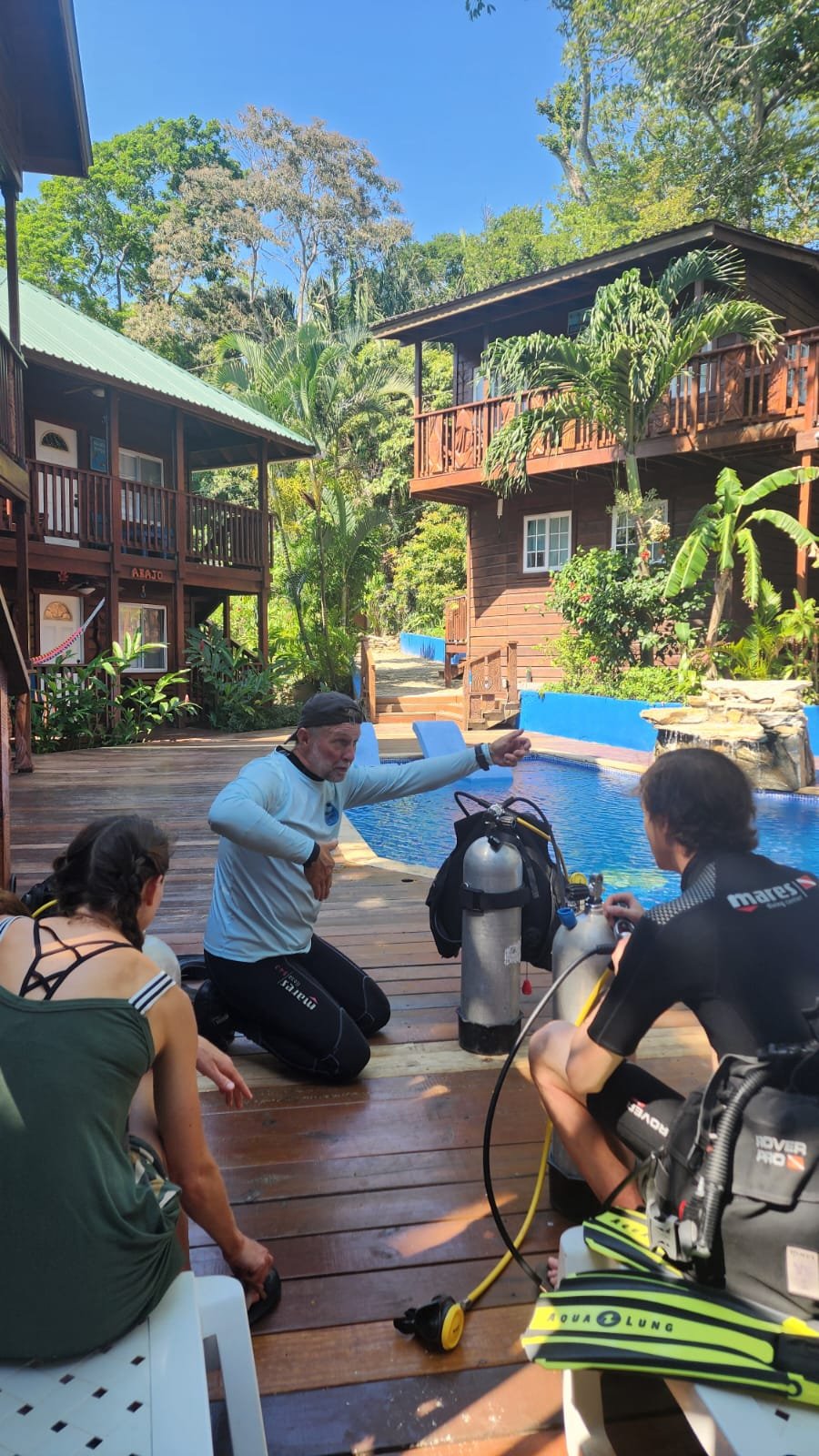 A Sandy Bay Divers instructor briefing two divers gearing up beside the Blue Bahia pool