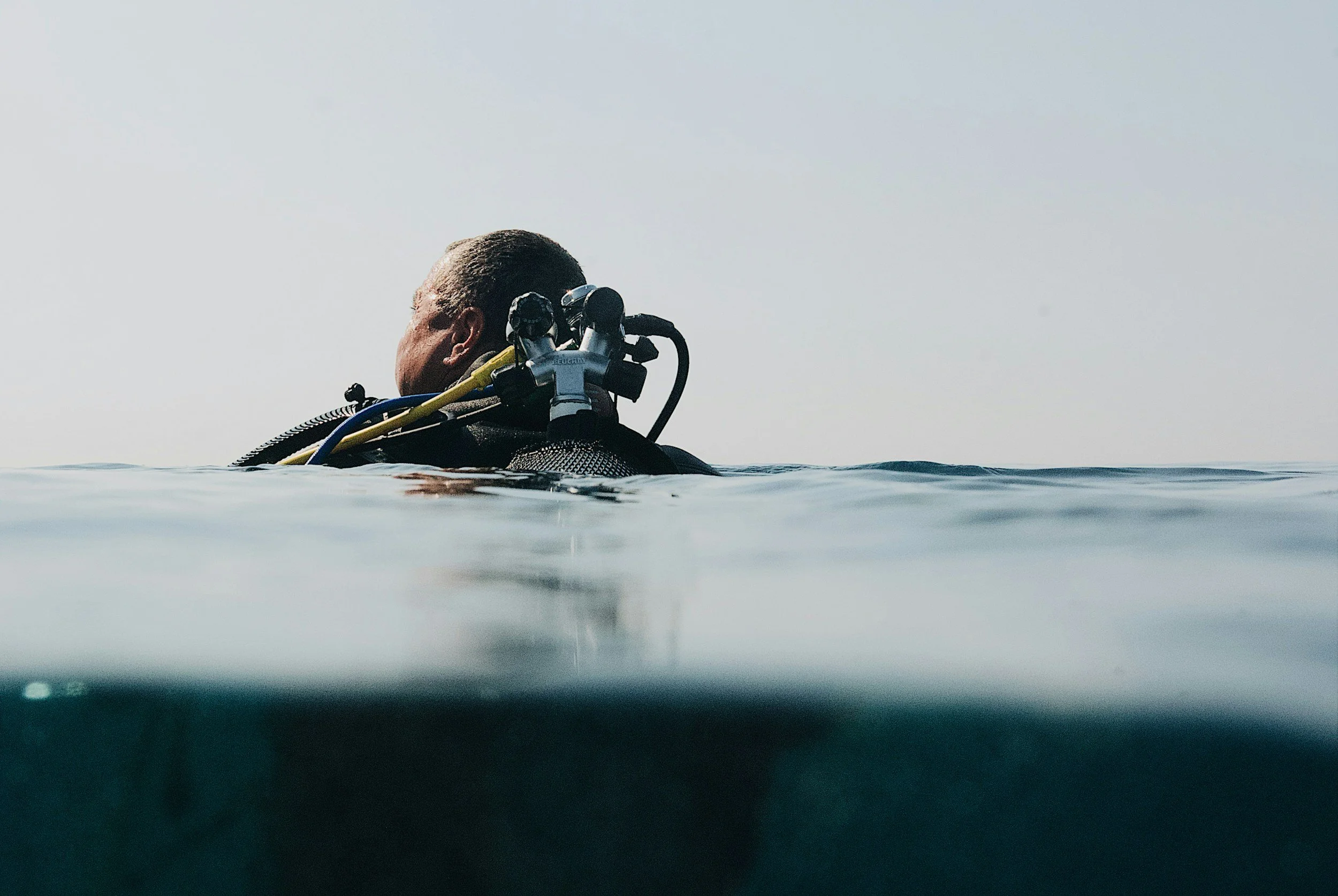 Scuba diver surfacing with full gear, checking equipment before a dive