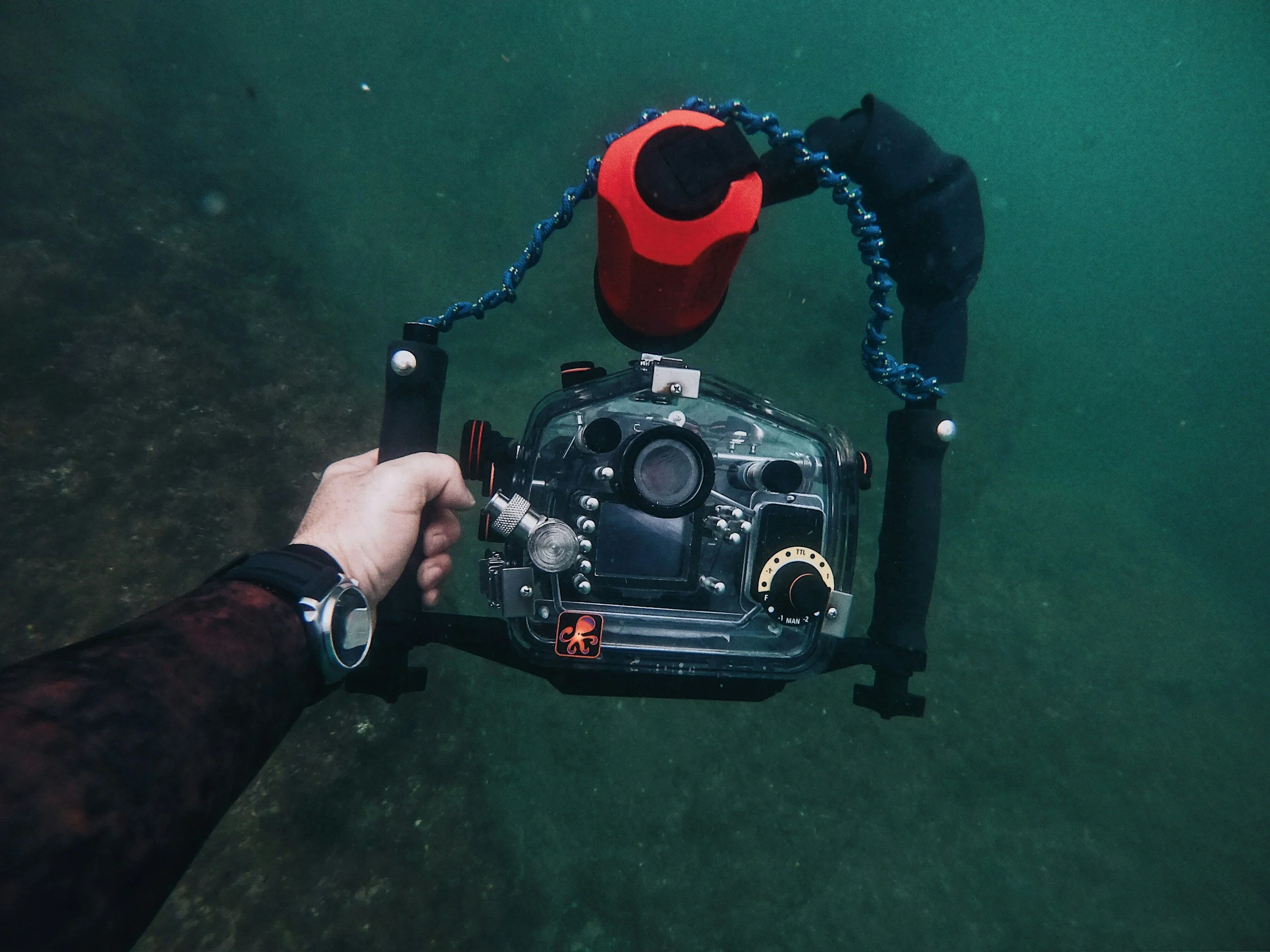 Underwater camera in a housing on a dual-handle tray with a light mounted on an arm