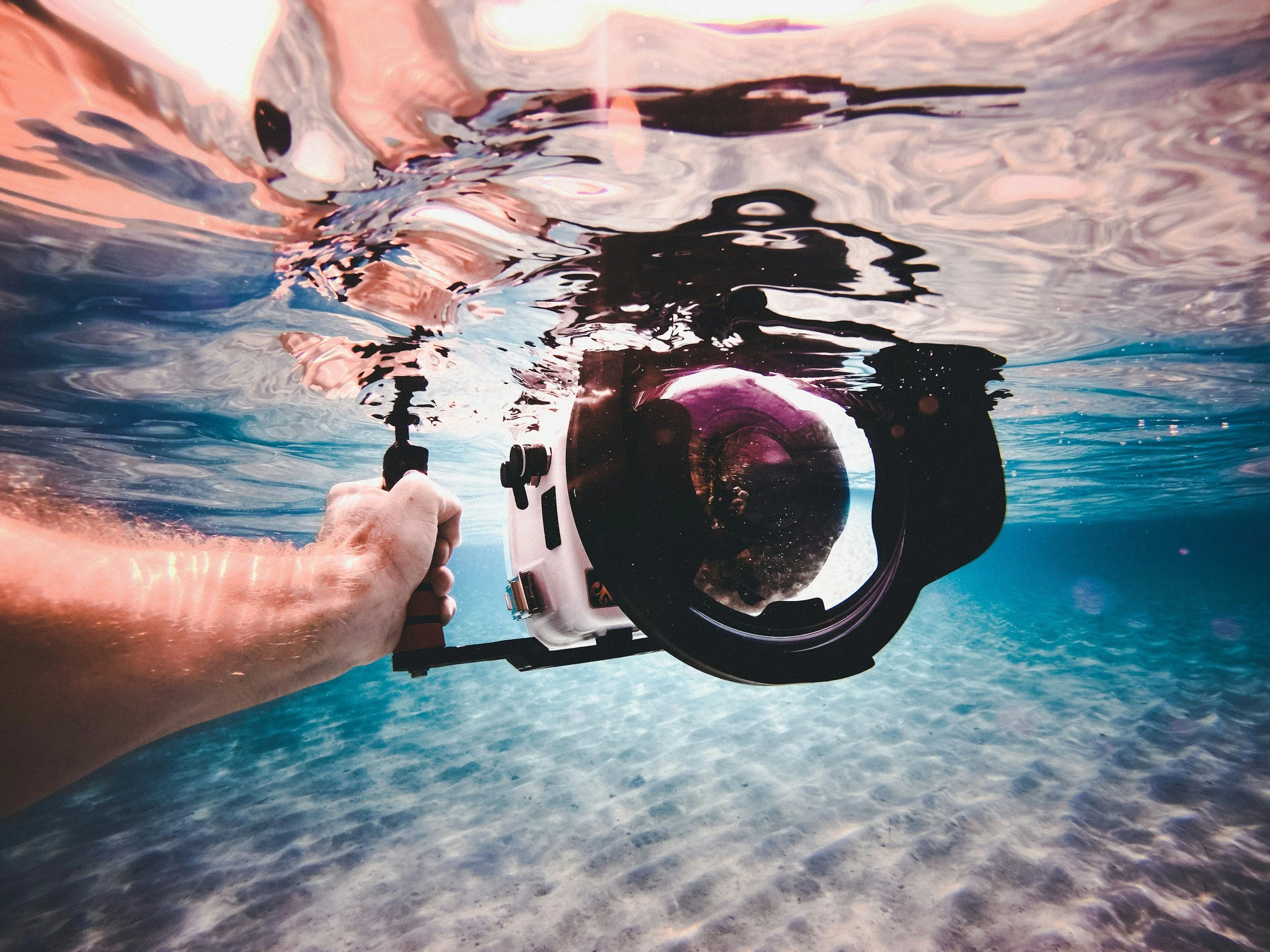 Camera with a dome port held just below the water surface for wide-angle underwater photography