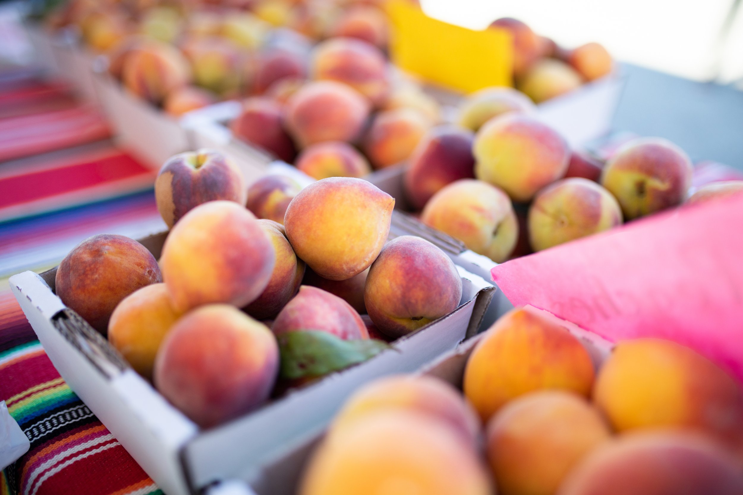 Ripe peaches in cardboard boxes at a market stall.