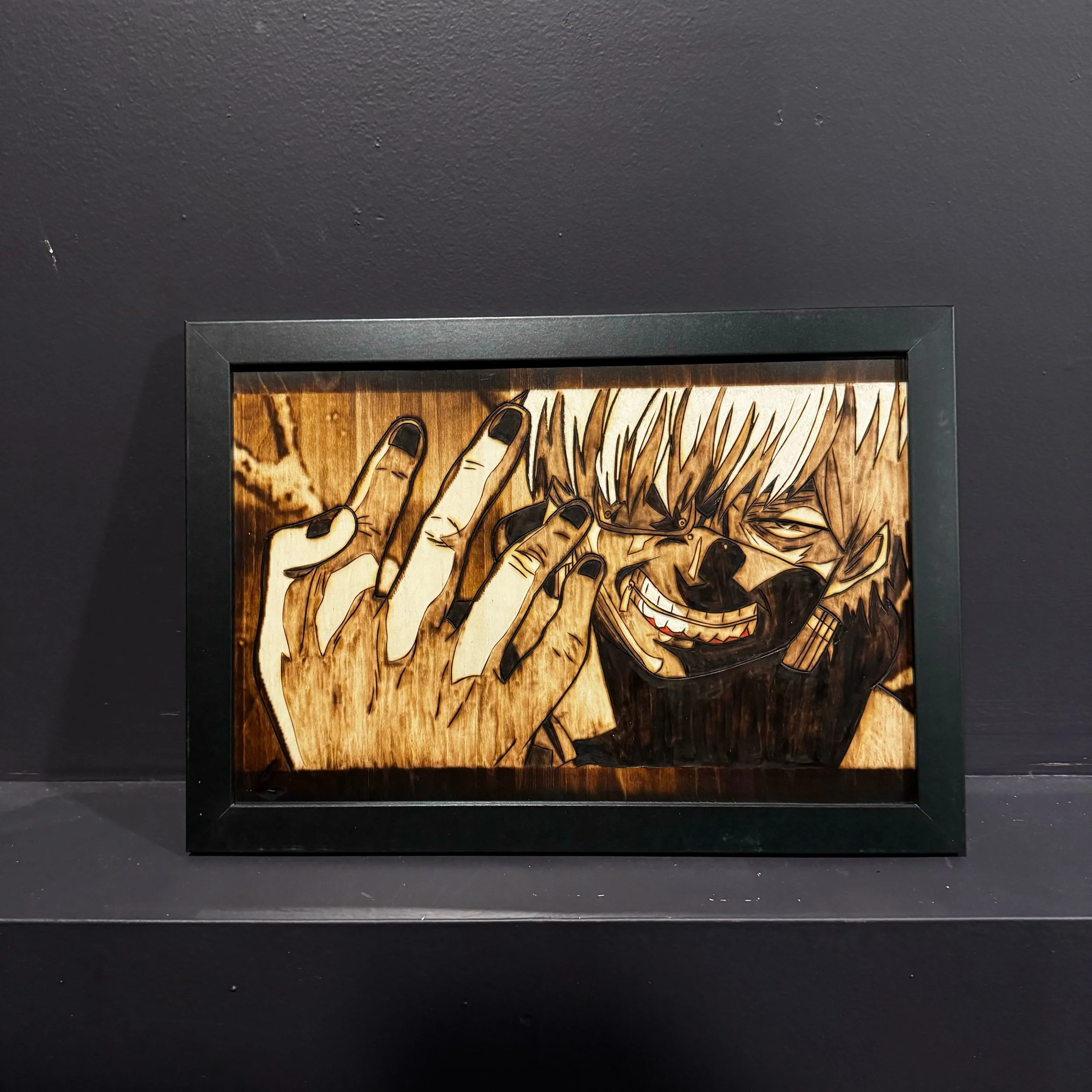 Wooden framed art depicting a person with blonde hair, glasses, and a black outfit, making a gesture with their hand, against a dark background.