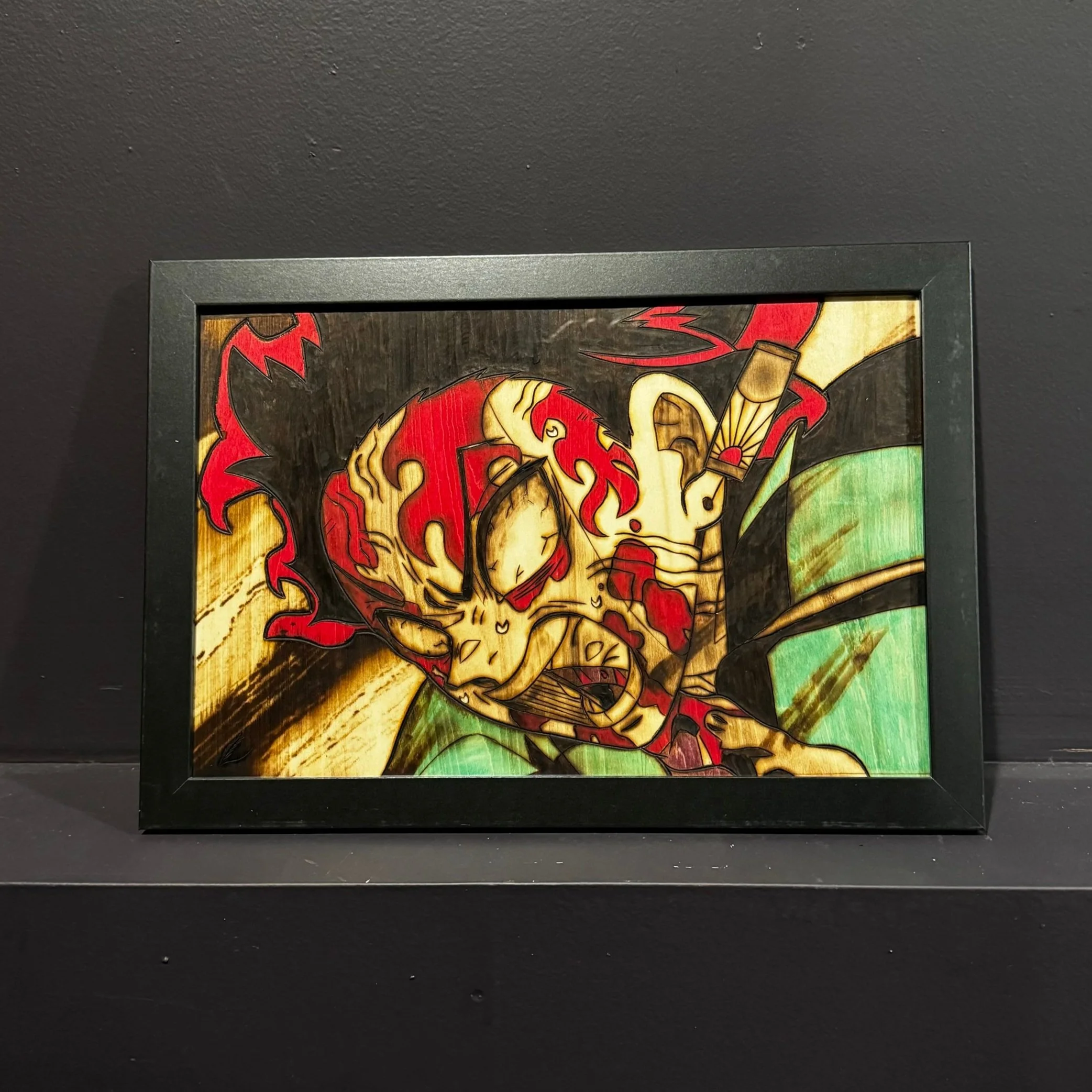Framed stained glass artwork of a samurai warrior with a fierce expression, red and yellow flames on his head, wearing traditional armor with green and black accents.