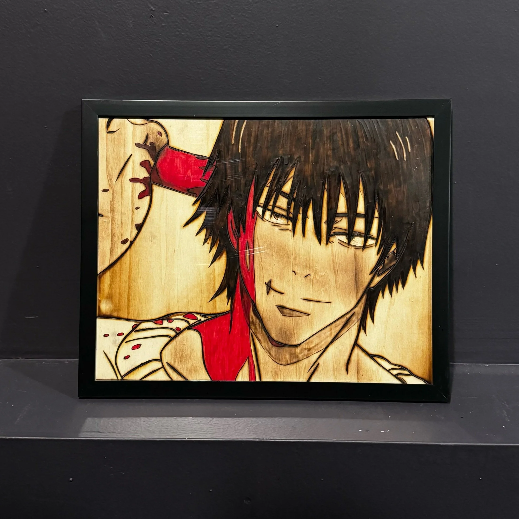 Wooden framed art of an anime character with dark hair, glasses, and a red shirt, smiling with a carefree expression.