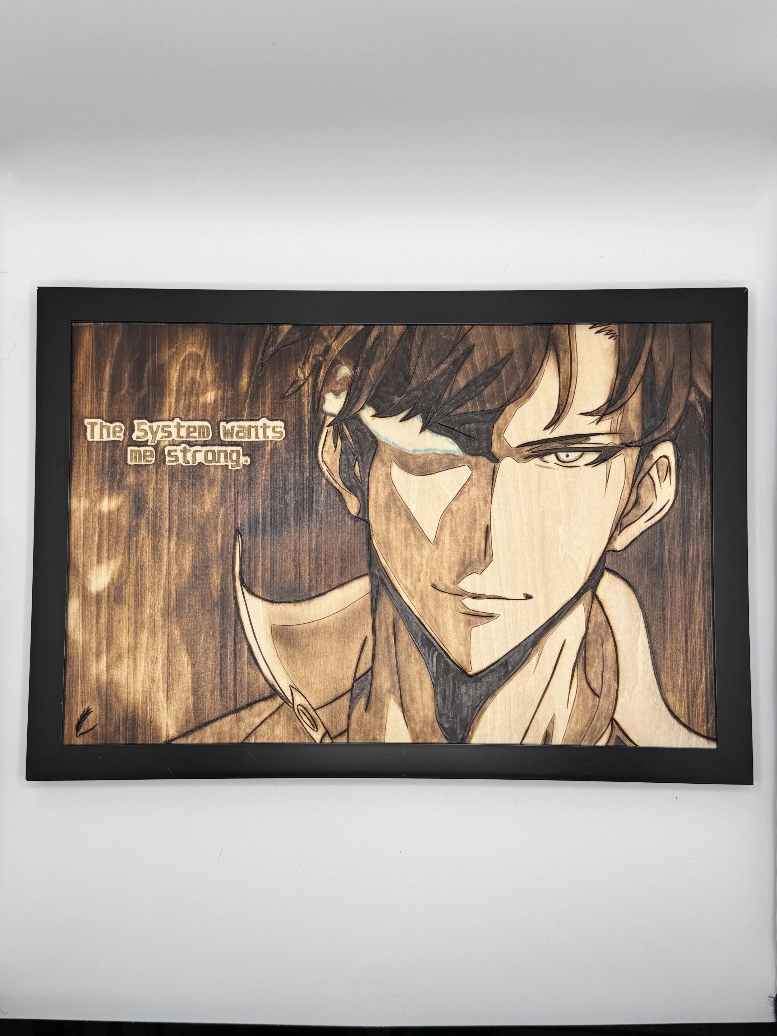 A framed wooden artwork of a male anime character with dark hair and an intense expression. Text on the artwork reads, 'The System wants me strong.'