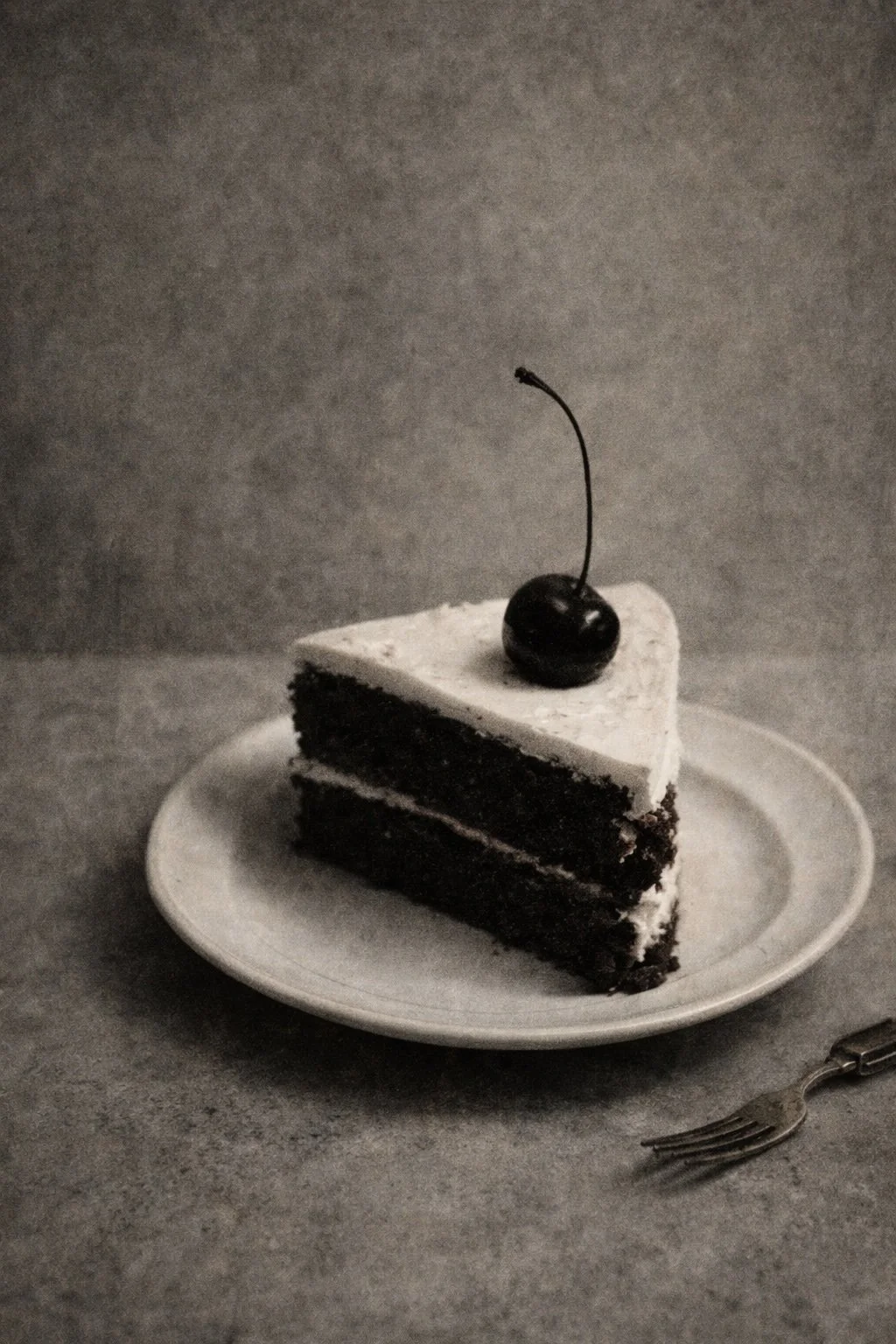 One Last Slice by Mattio – atmospheric contemporary still life depicting a slice of cake topped with a cherry in soft monochrome tones, celebrating quiet moments through rich textures and subtle detail, presented by Landson Studios.