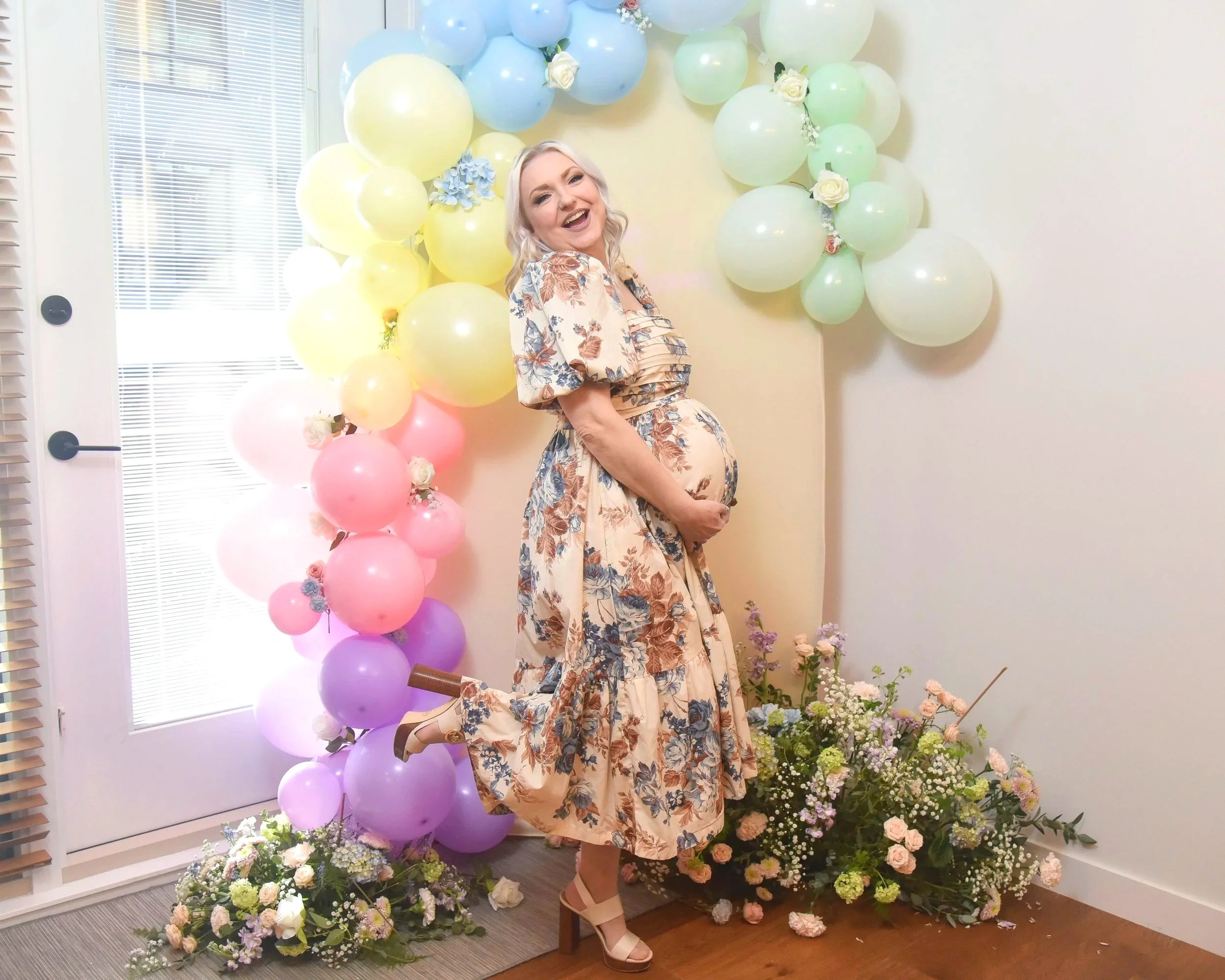 Mom to be posing in front of balloon backdrop