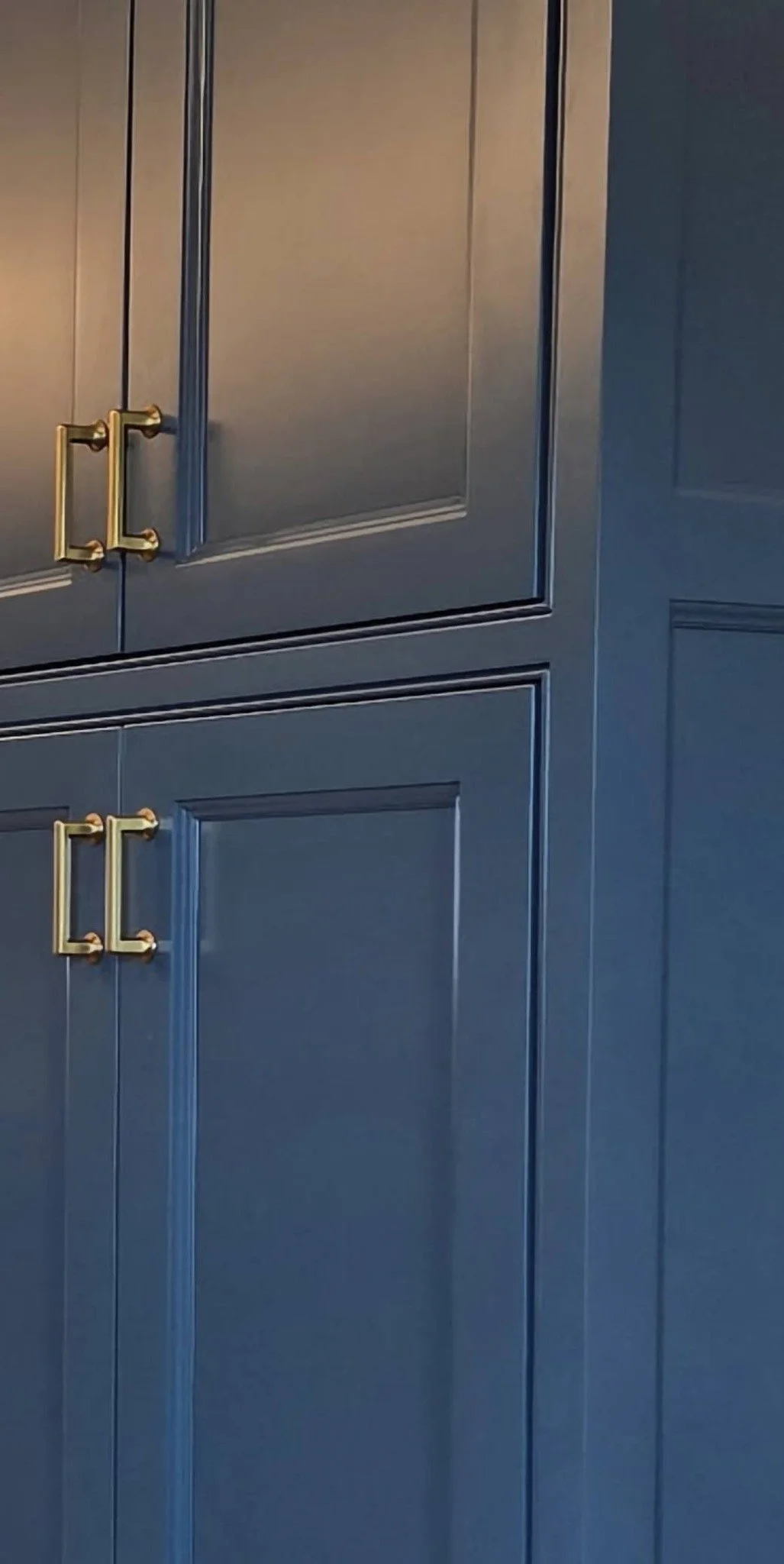 Blue kitchen cabinets with gold handles.