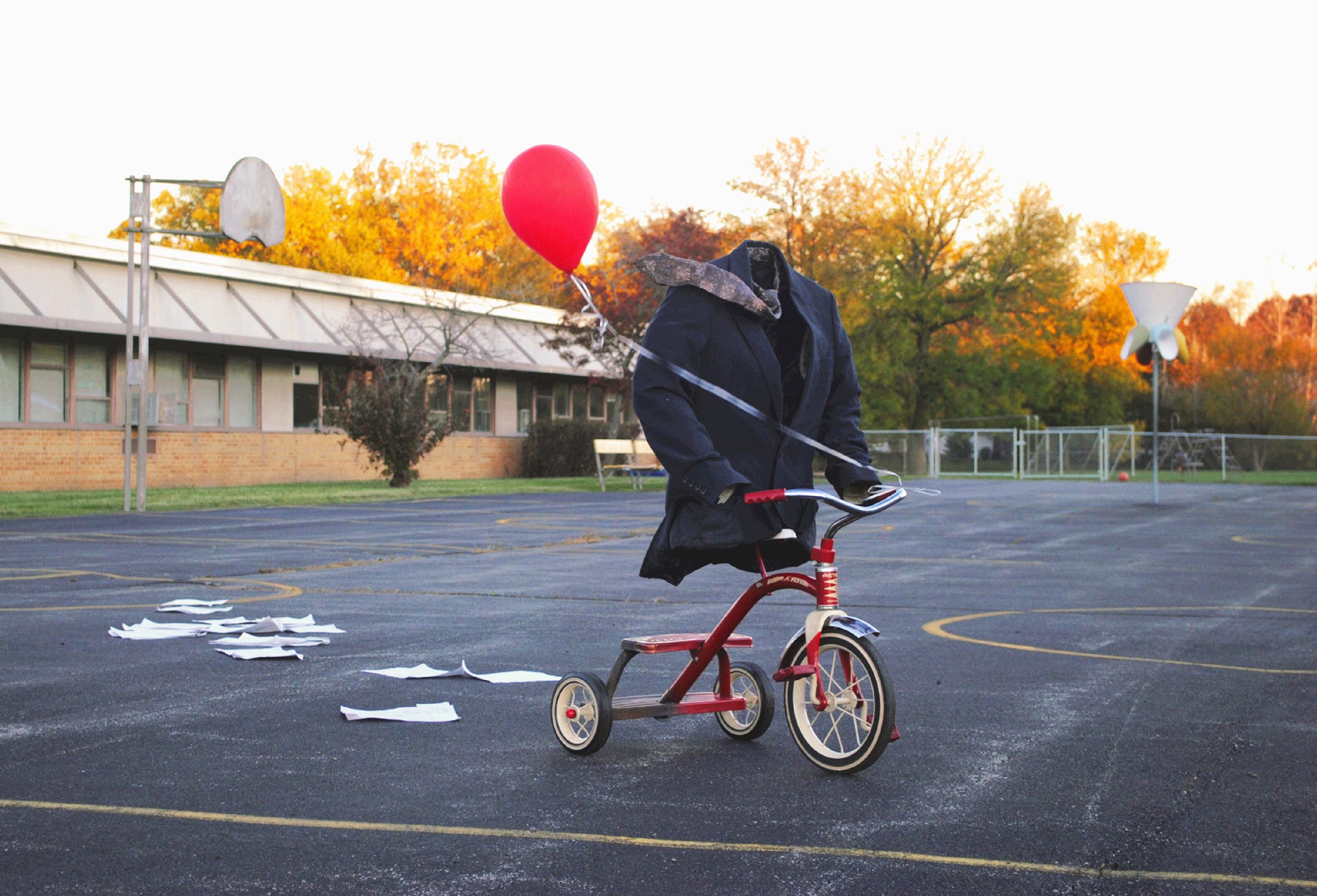 THE SUIT - A temporary site specific installation. Tricycle, Suit Coat, Tie, Red Balloon, Loose Invoices and Playground. 7' x 2' x 5'