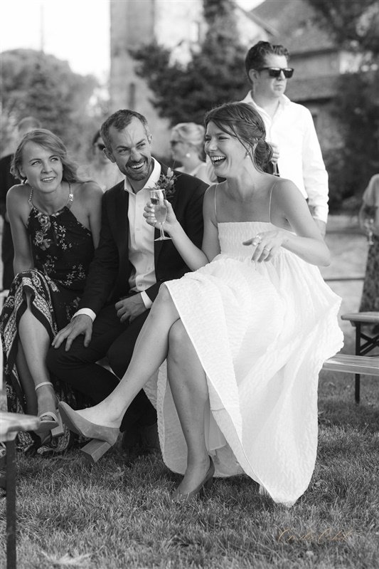The bride laughs as she listens to speeches. Photo in black and white