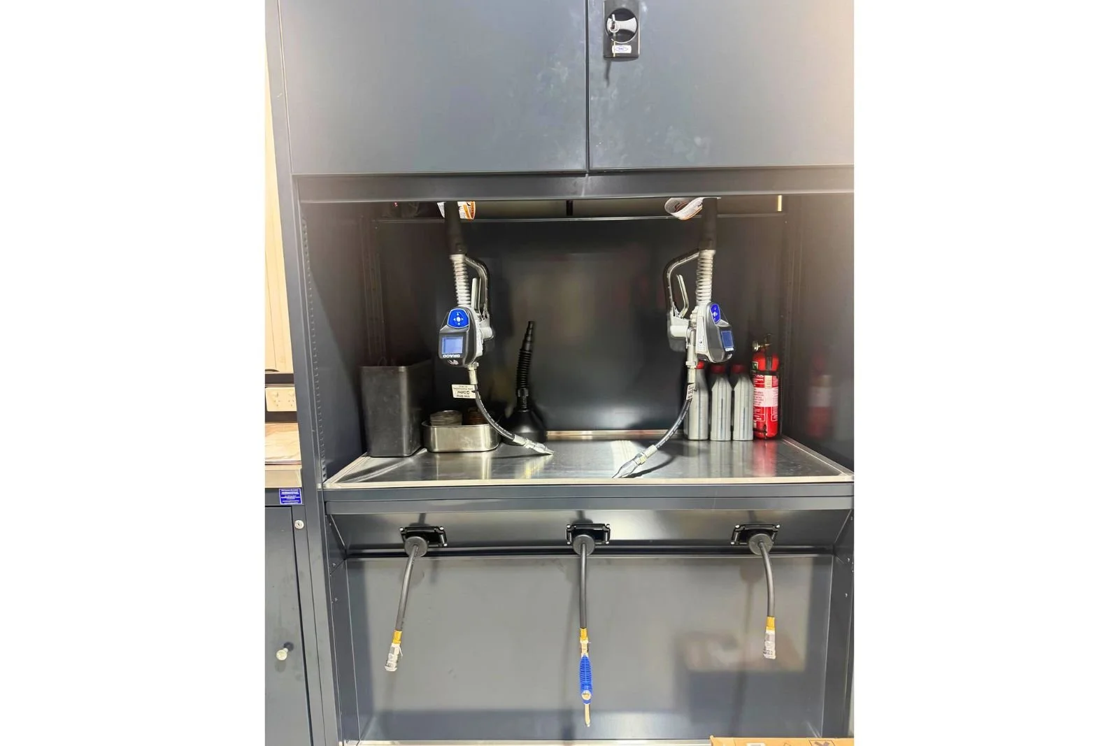 Graco fluid management oil dispensing cabinet with digital metered oil guns installed in automotive workshop.