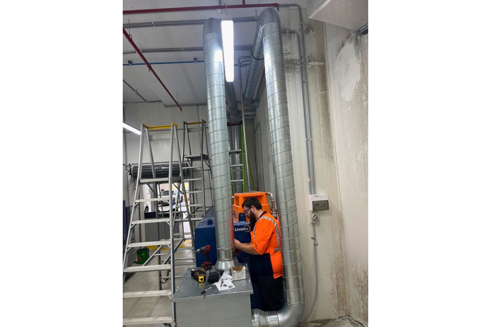 Automotive workshop exhaust fan and ducting installed to safely extract fumes from service bays.