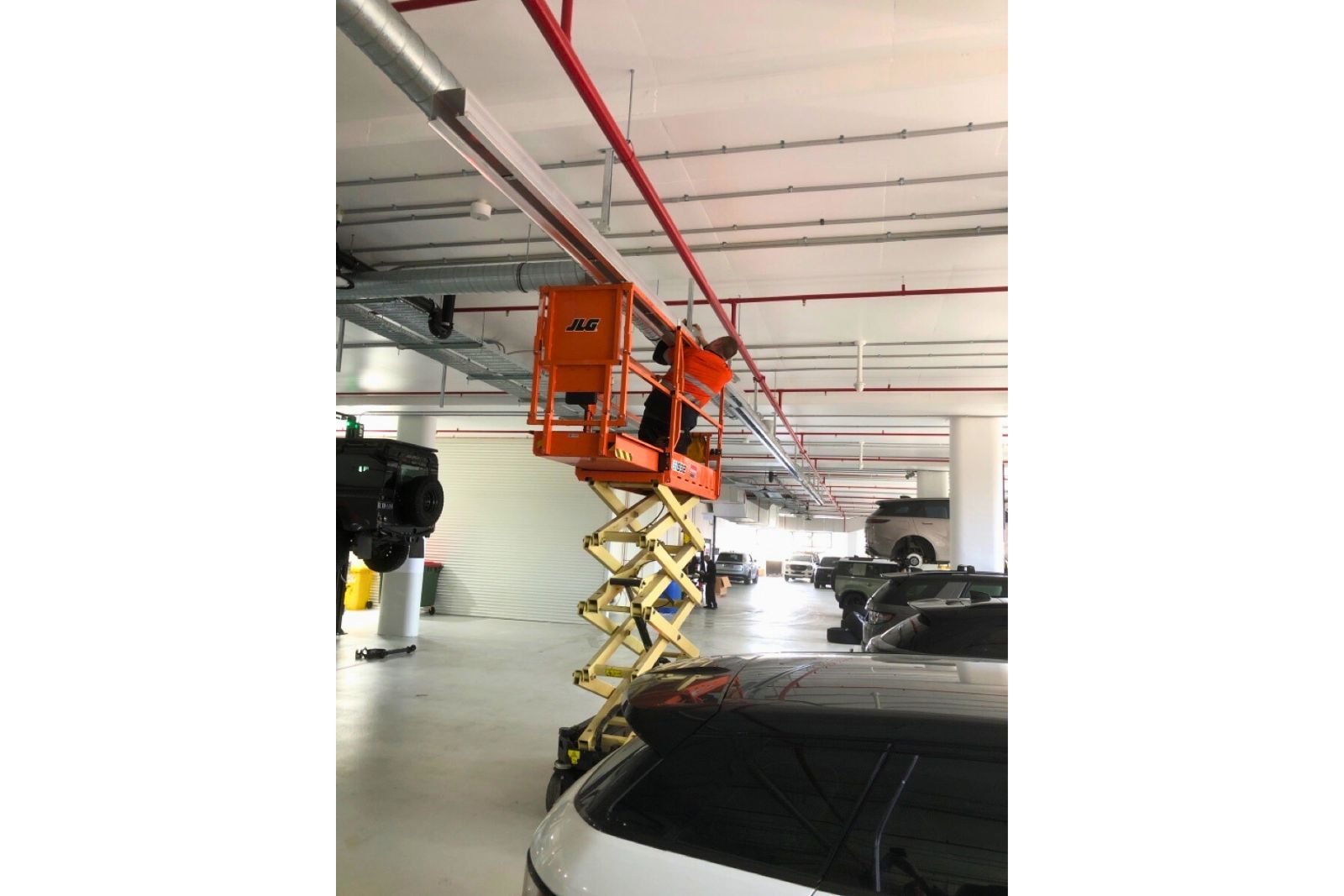 Technician installing automotive workshop ventilation ducting during a fitout project in Artarmon NSW.