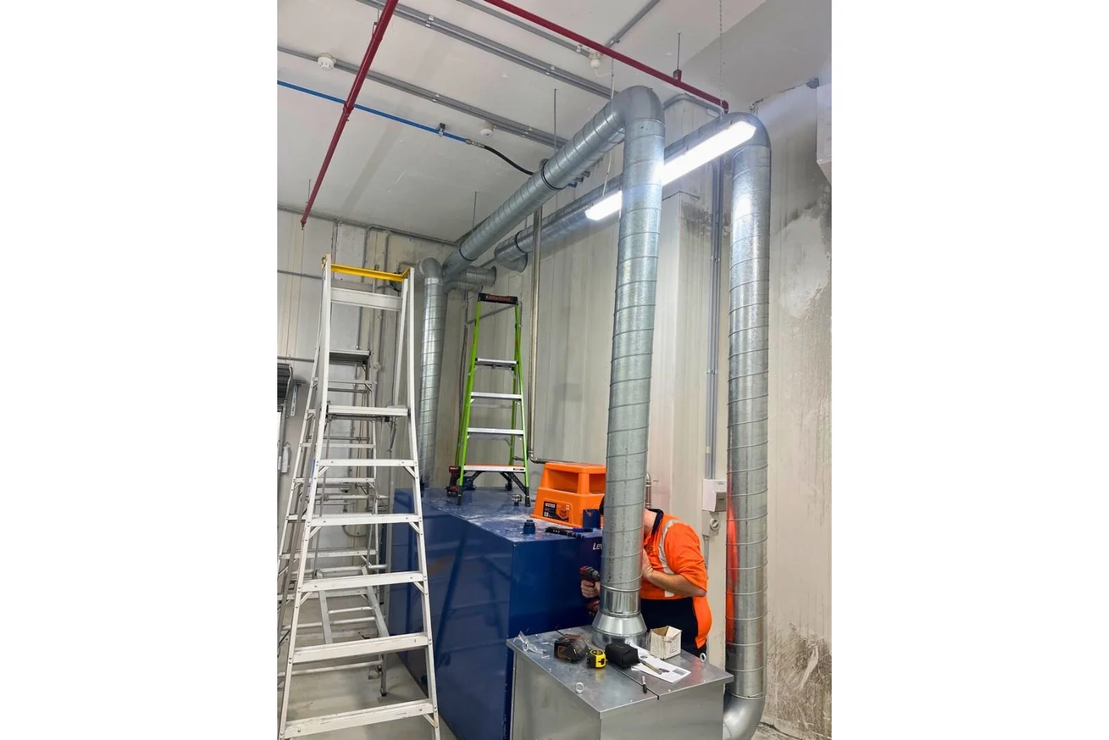 Workshop exhaust ducting routed to fan motor during ventilation system installation in Artarmon NSW.