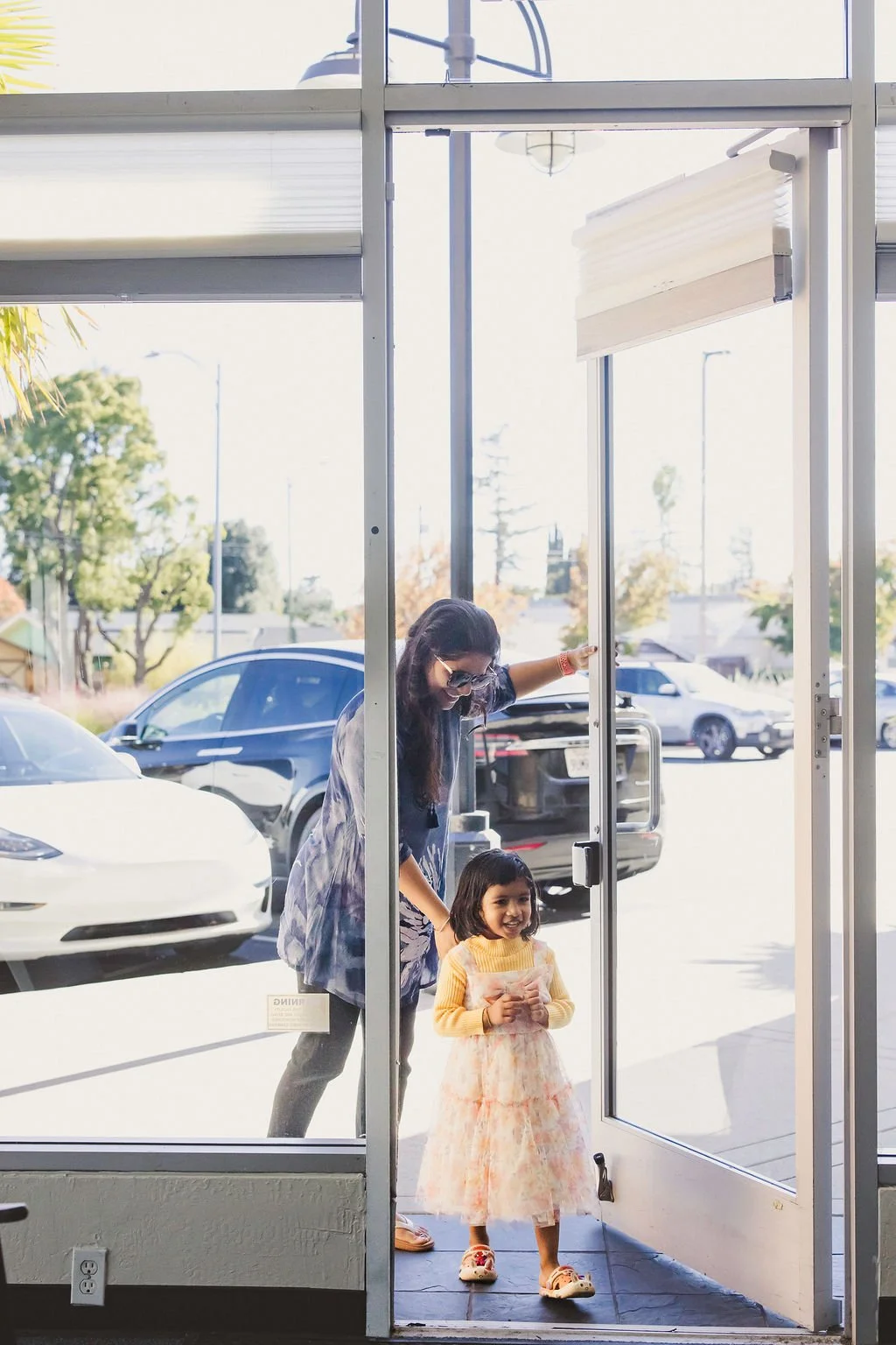 A mother and daughter enter the studio through the front glass door. 