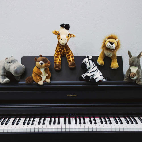 Stuffed animals sit on top of a black piano
