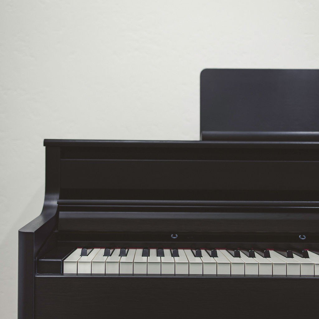 The left side of a black electric piano against a white wall