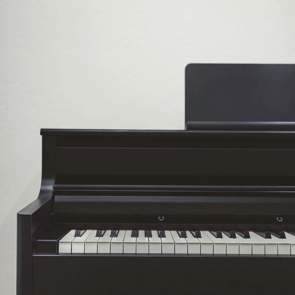 The left side of a black electric piano against a white wall
