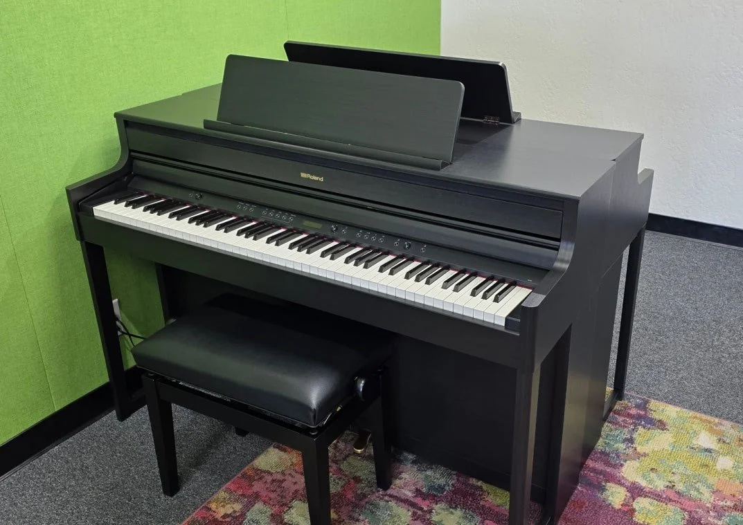 A piano keyboard and bench sit in a piano studio
