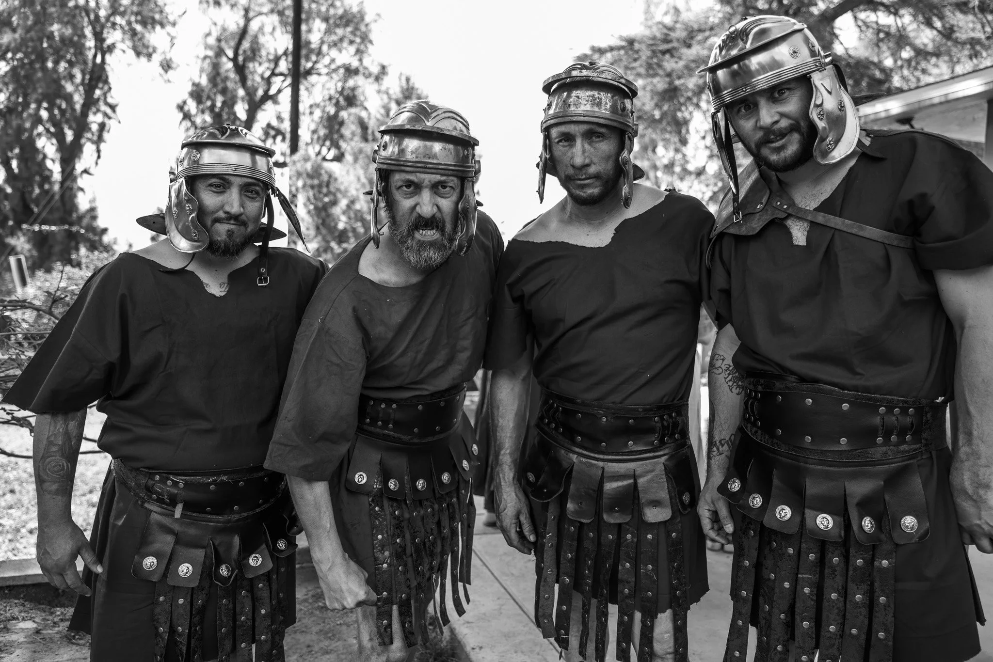 Four men dressed in medieval armor standing outdoors, looking at the camera.
