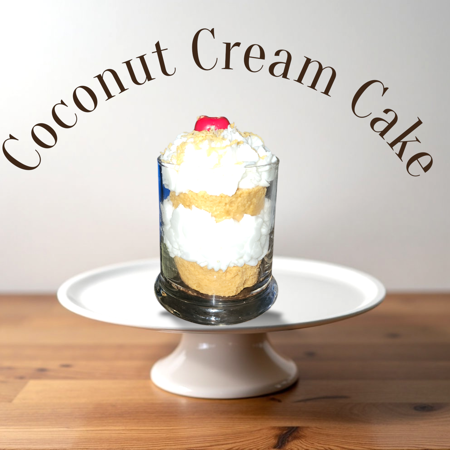 A Dessert Candle 

A Dessert Candle coconut cream cake , including whipped cream, cakes, and a cherry, placed on a white cake stand on a wooden surface.