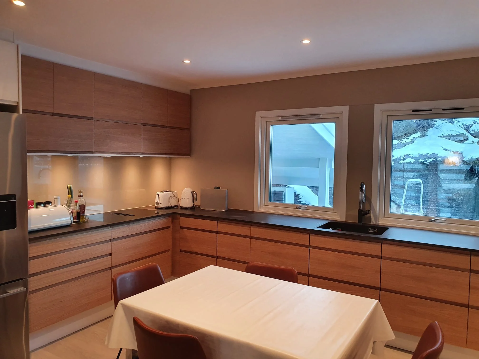 Warm and modern kitchen redesign with brown cabinets and a table in the middle