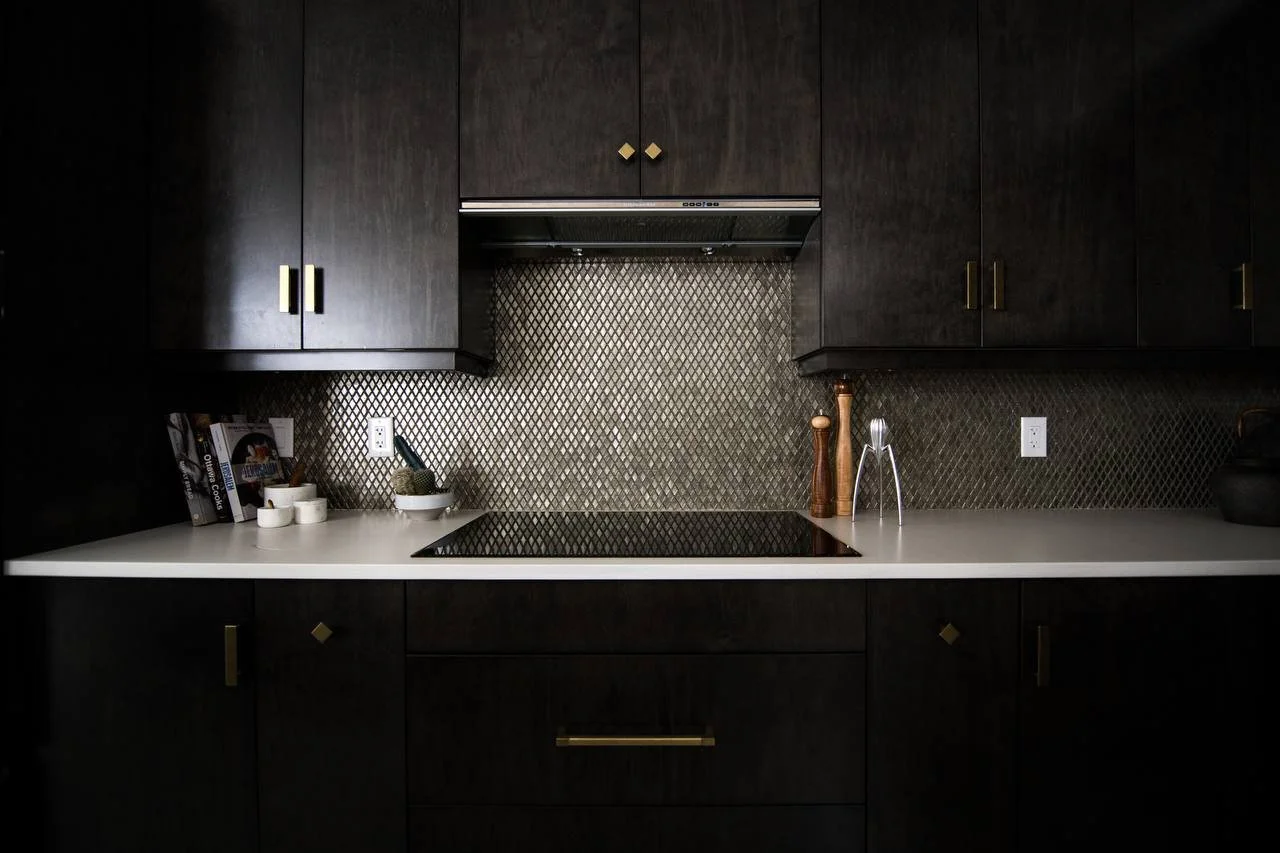 a luxurious and modern kitchen with dark wooden cabinets and a white countertop. The cabinets are dark brown with gold handles