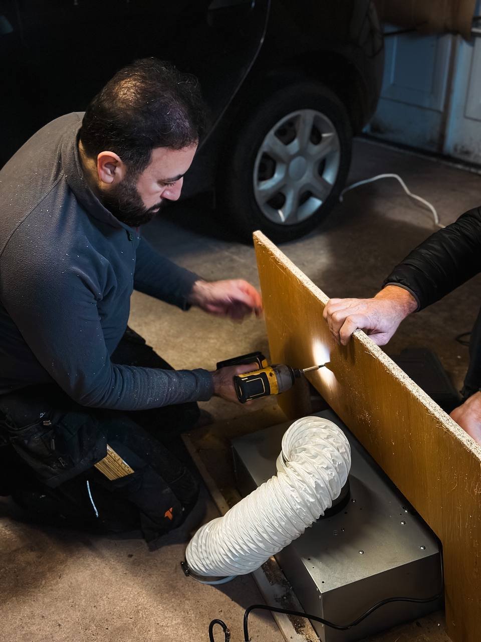 A handyman drilling into a wooden piece in a basement