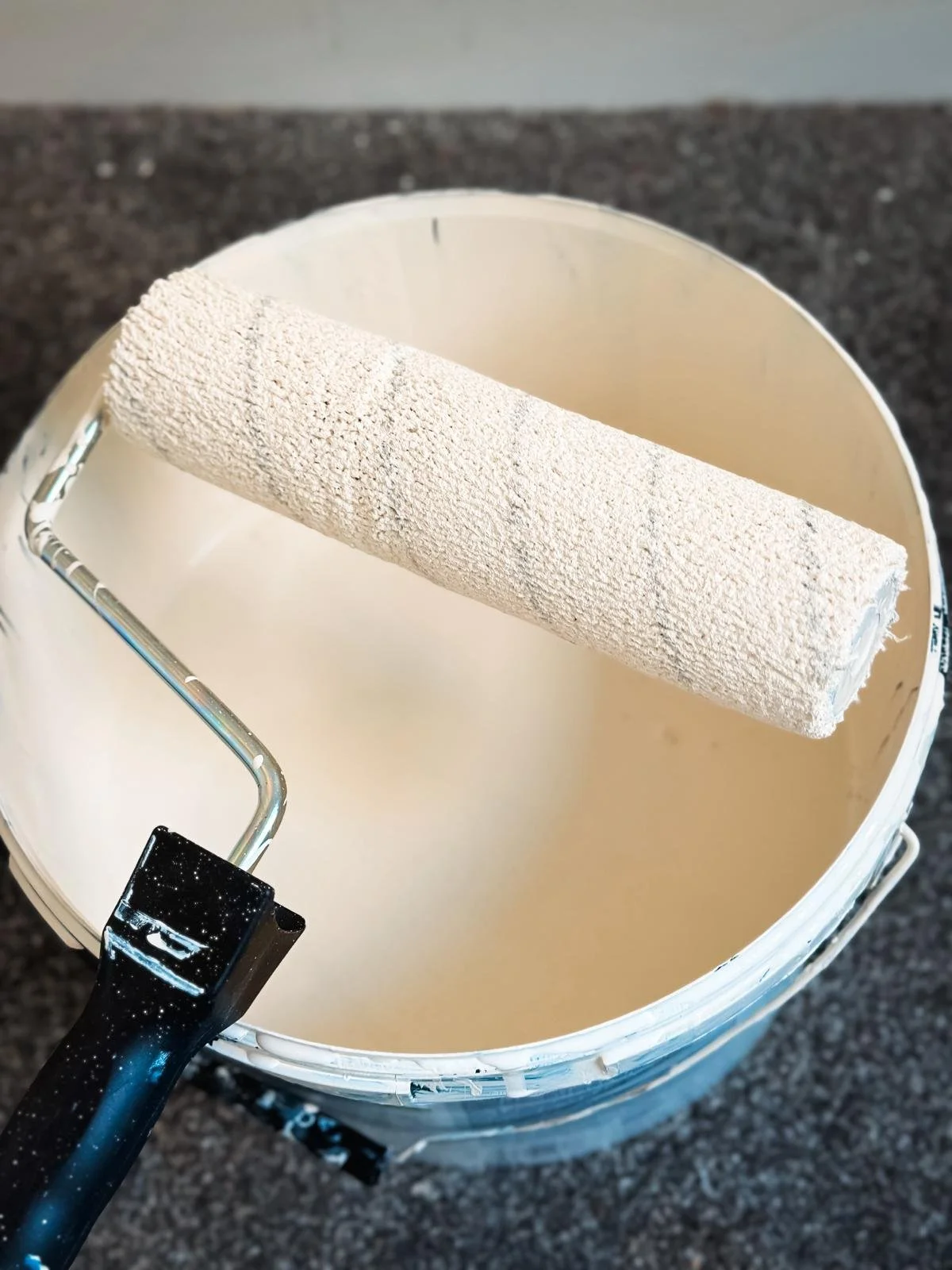 A paint roll on top of some creamy  paint