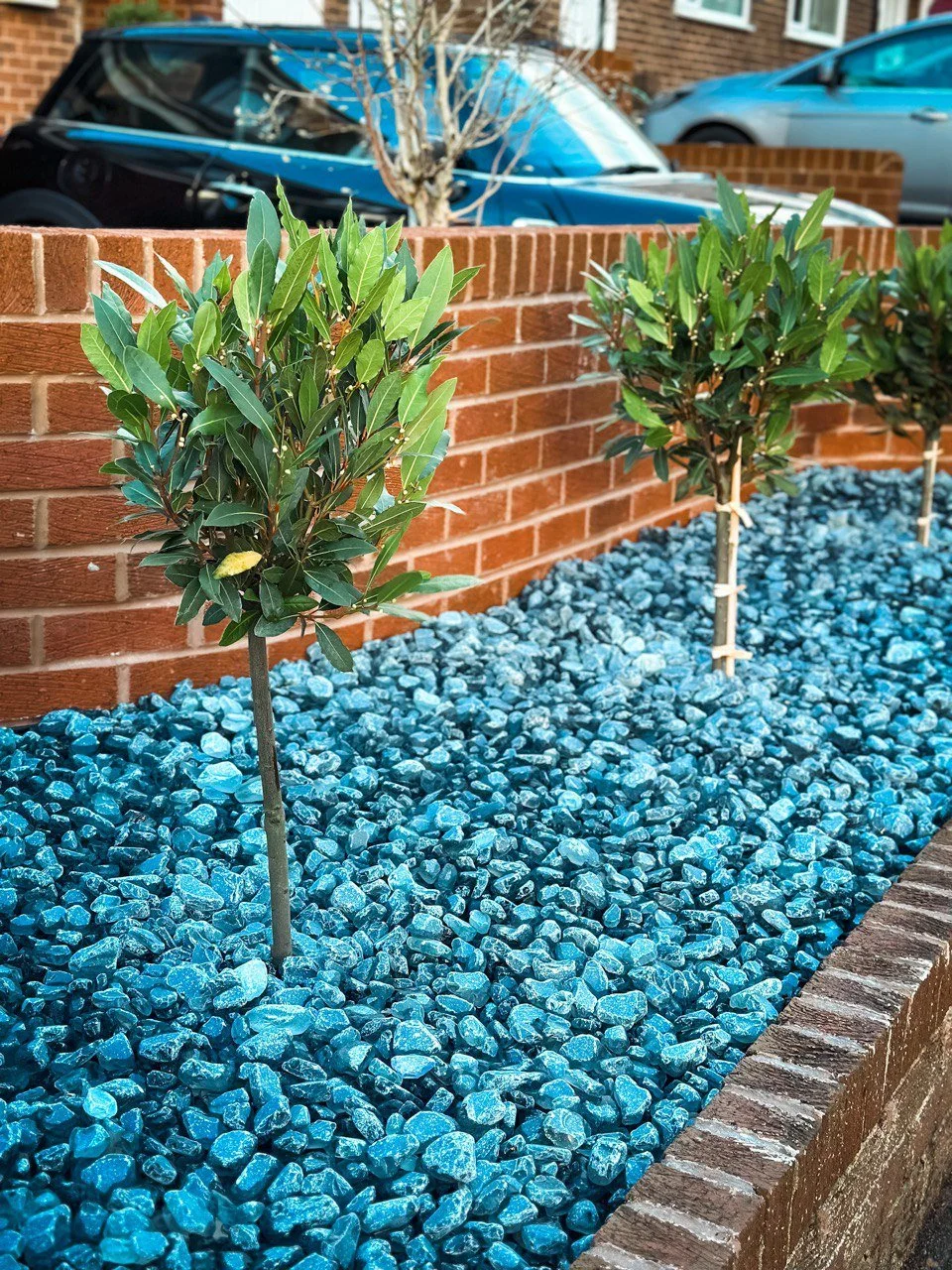 An outside of the house photo, a orange wall with gravel and 2 trees