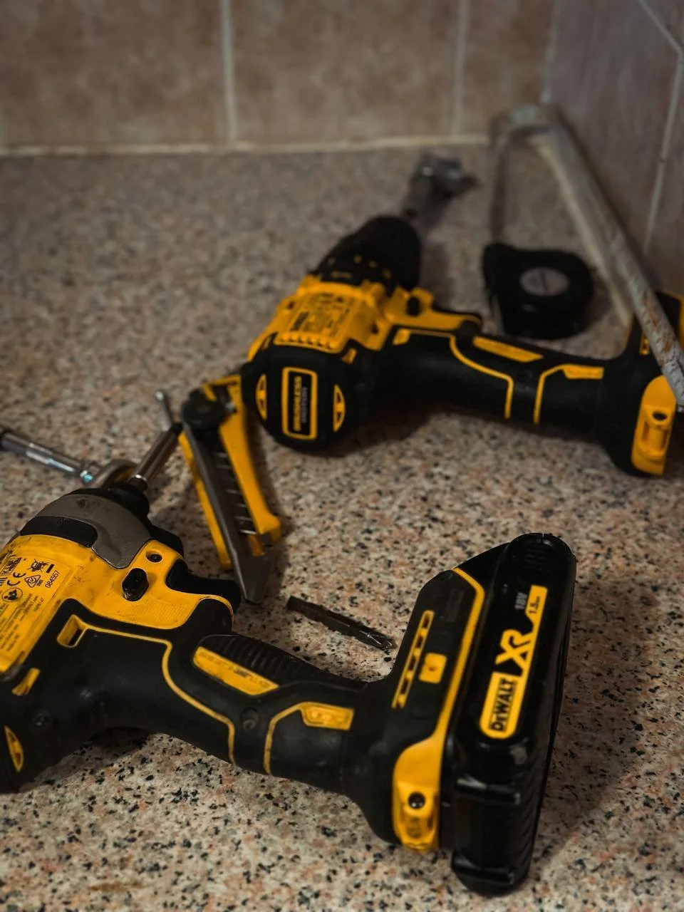 Yellow drills on a table with other handyman tools on a kitchen worktop