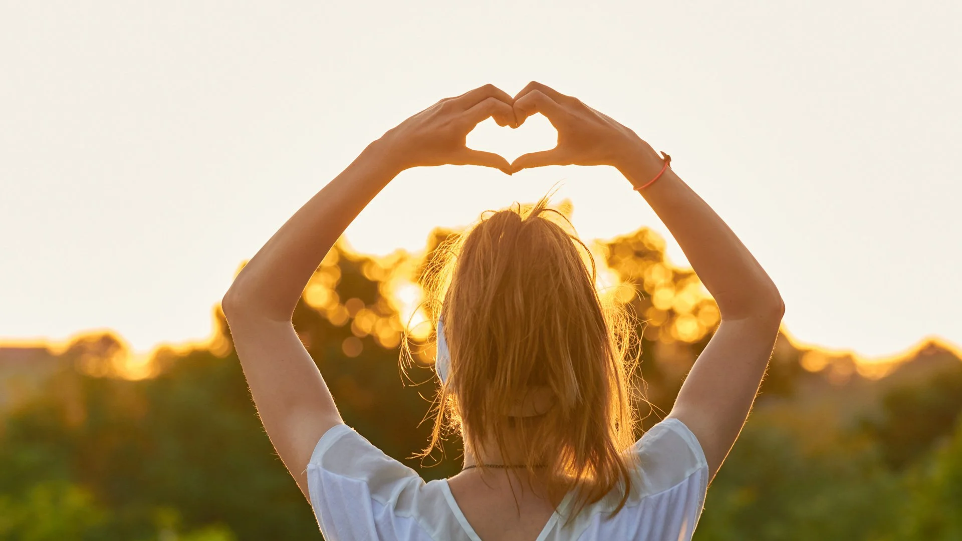 Mother facing divorce creating heart shape with her hands above her head.