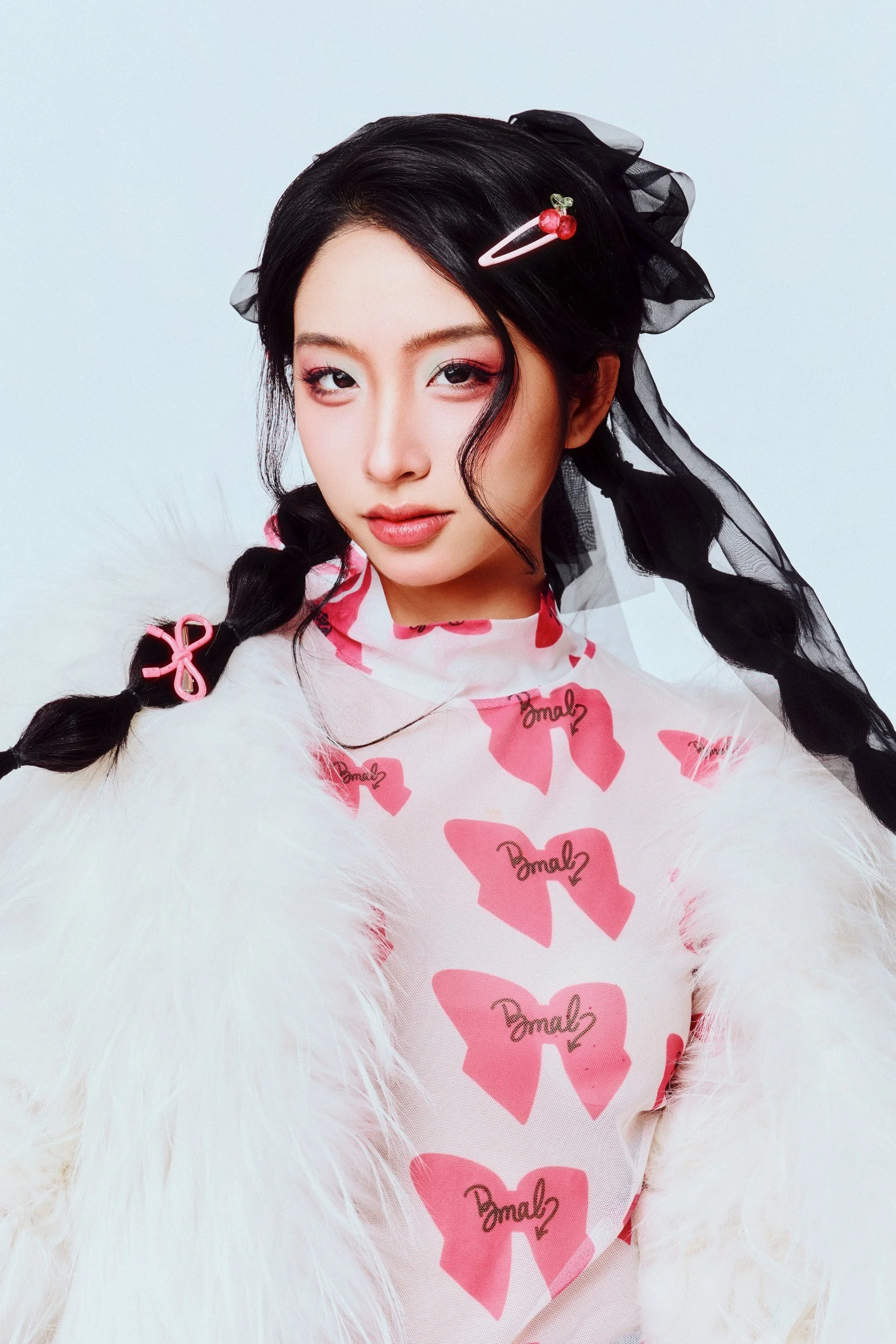 Studio portrait of a woman with braids in a pink top and white faux fur