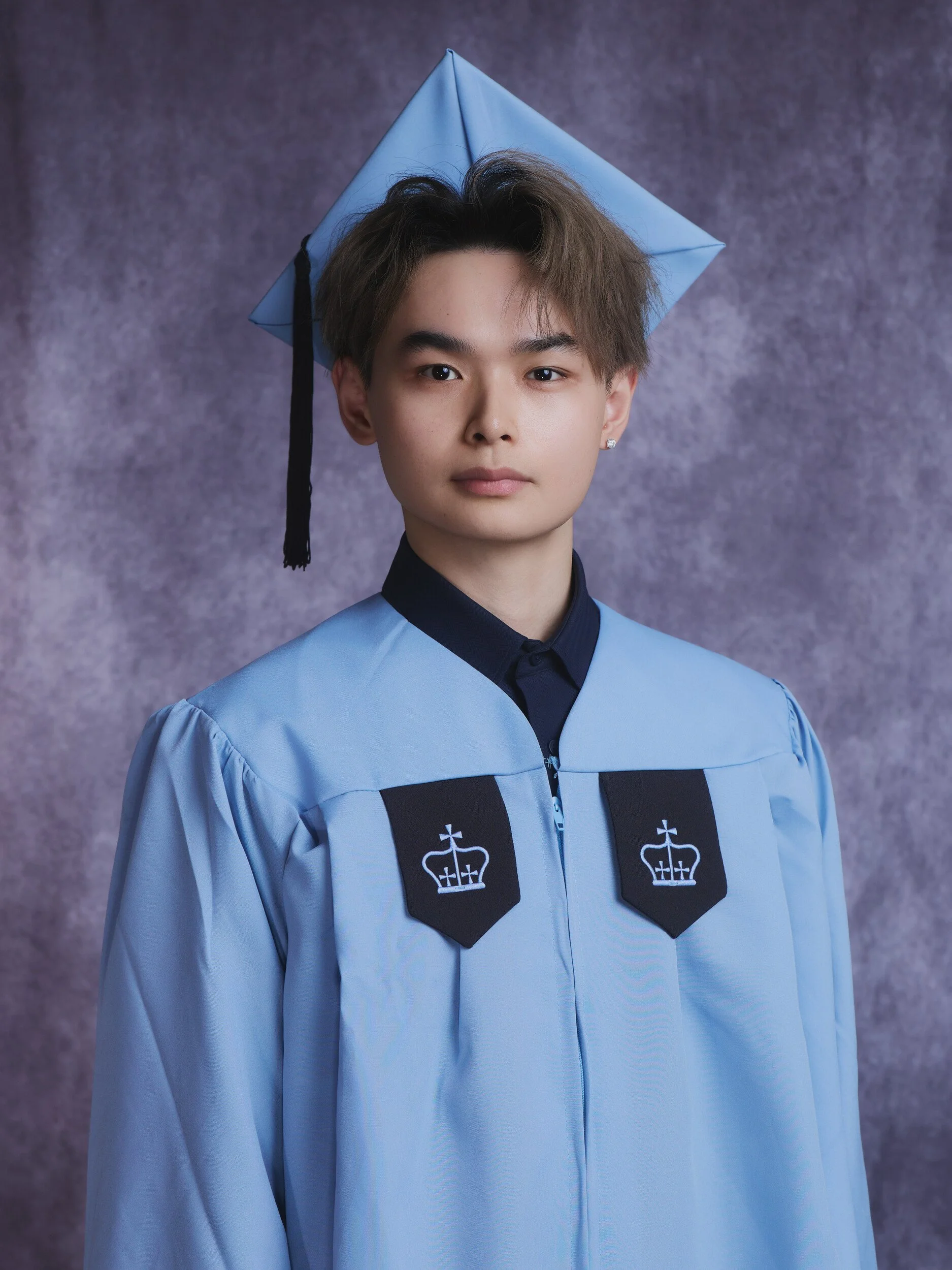 Columbia graduation portrait of a young man in a light blue gown and cap