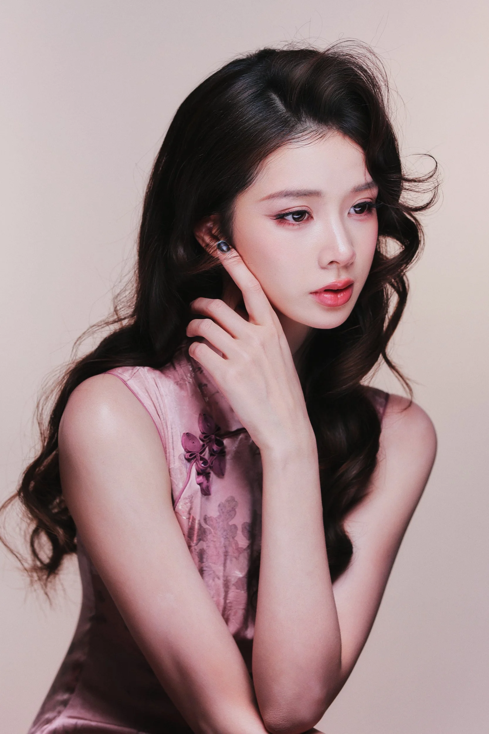 Studio portrait of a woman in a pink qipao with a soft smile