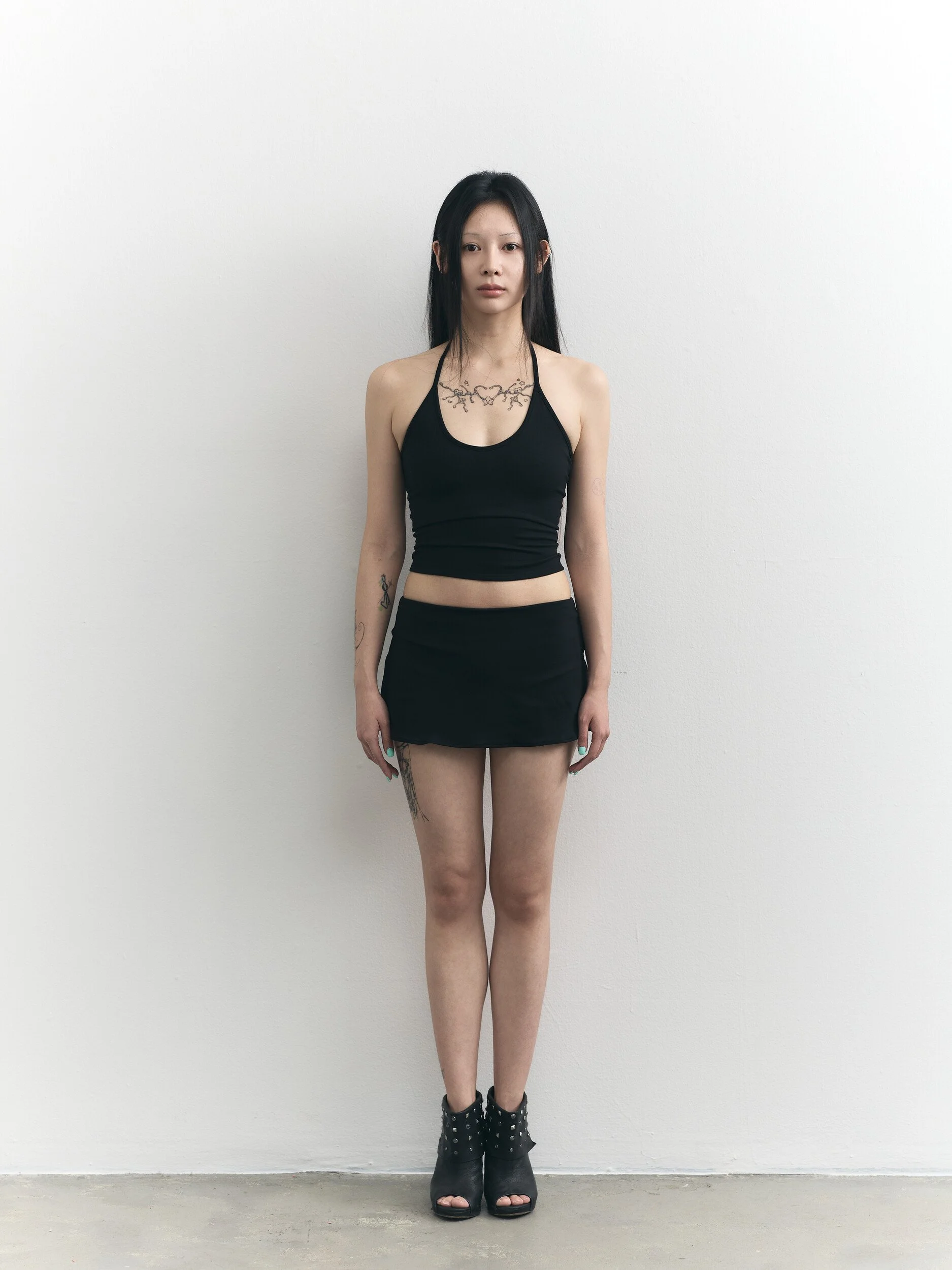 Model digitals: full-length front view of the model in a black halter top and mini skirt