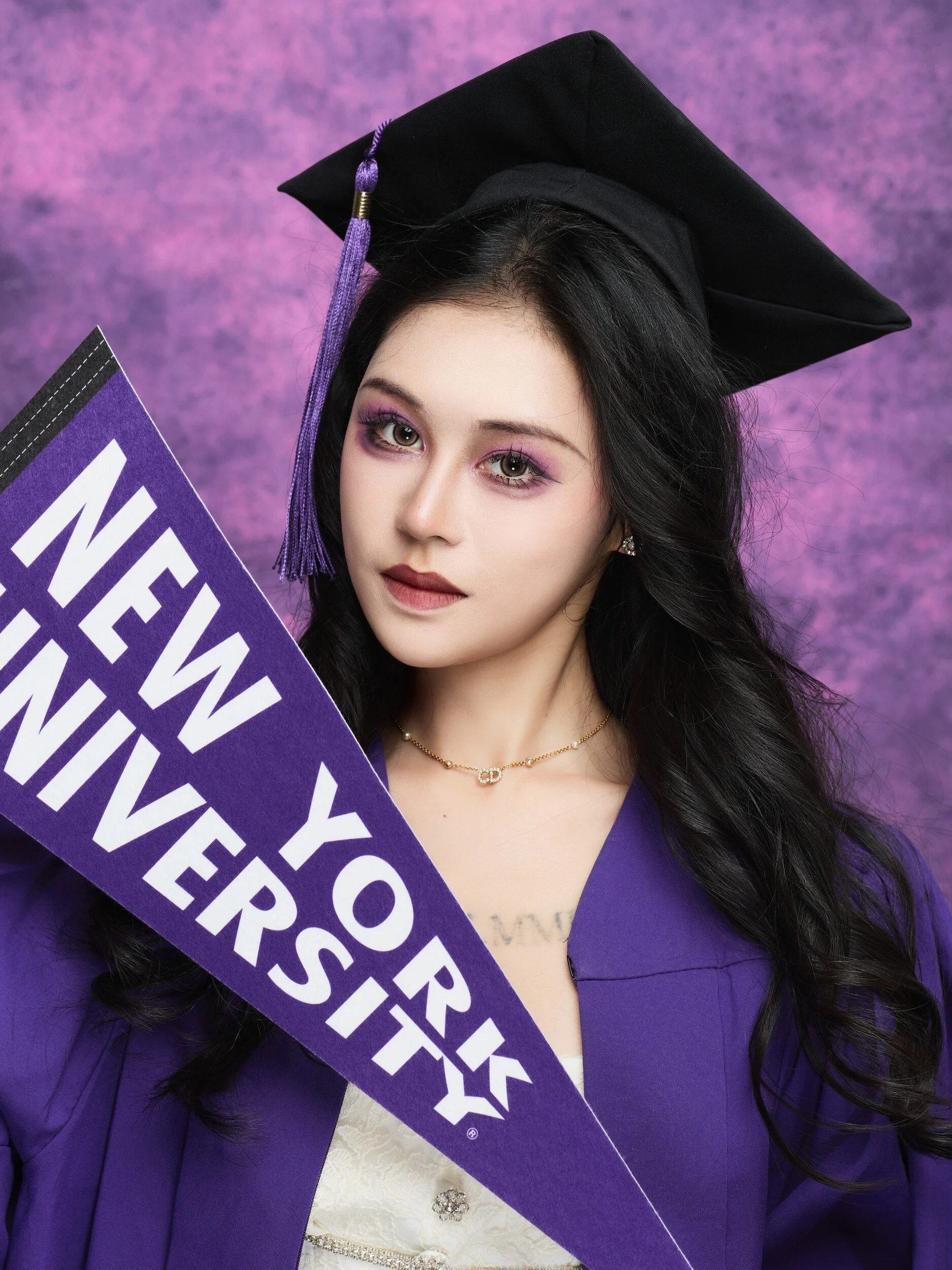 NYU graduation portrait of a woman with a New York University pennant