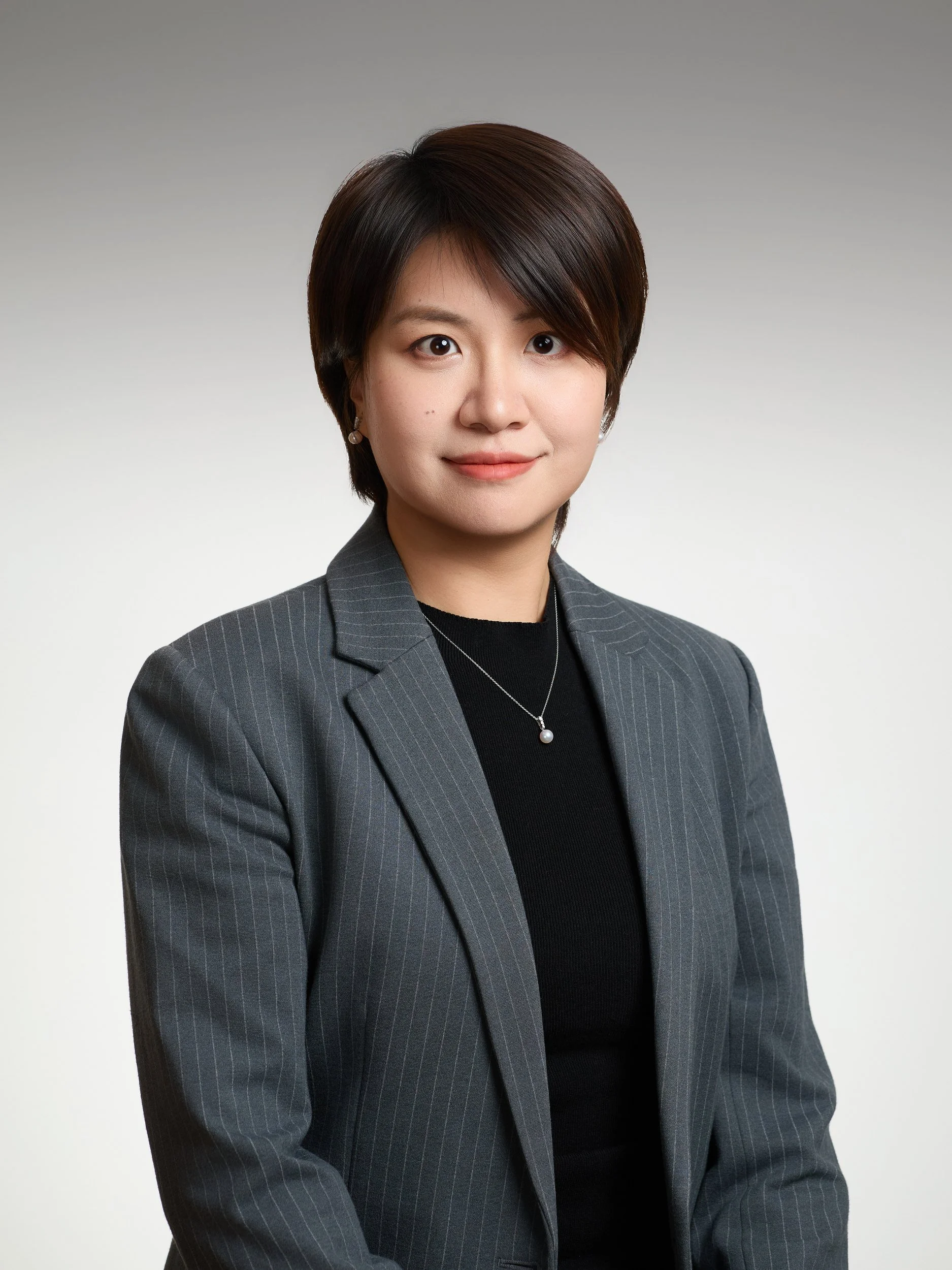 Corporate headshot of a woman with short hair in a grey pinstripe blazer