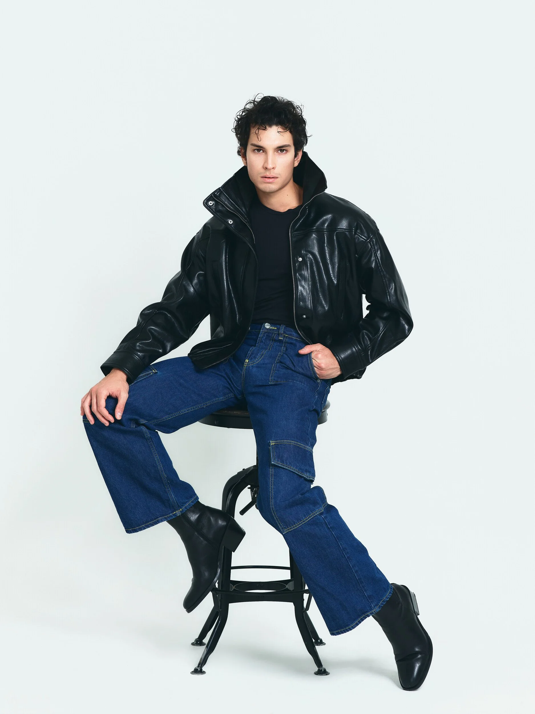 Model digitals: the model seated on a stool in a black leather jacket