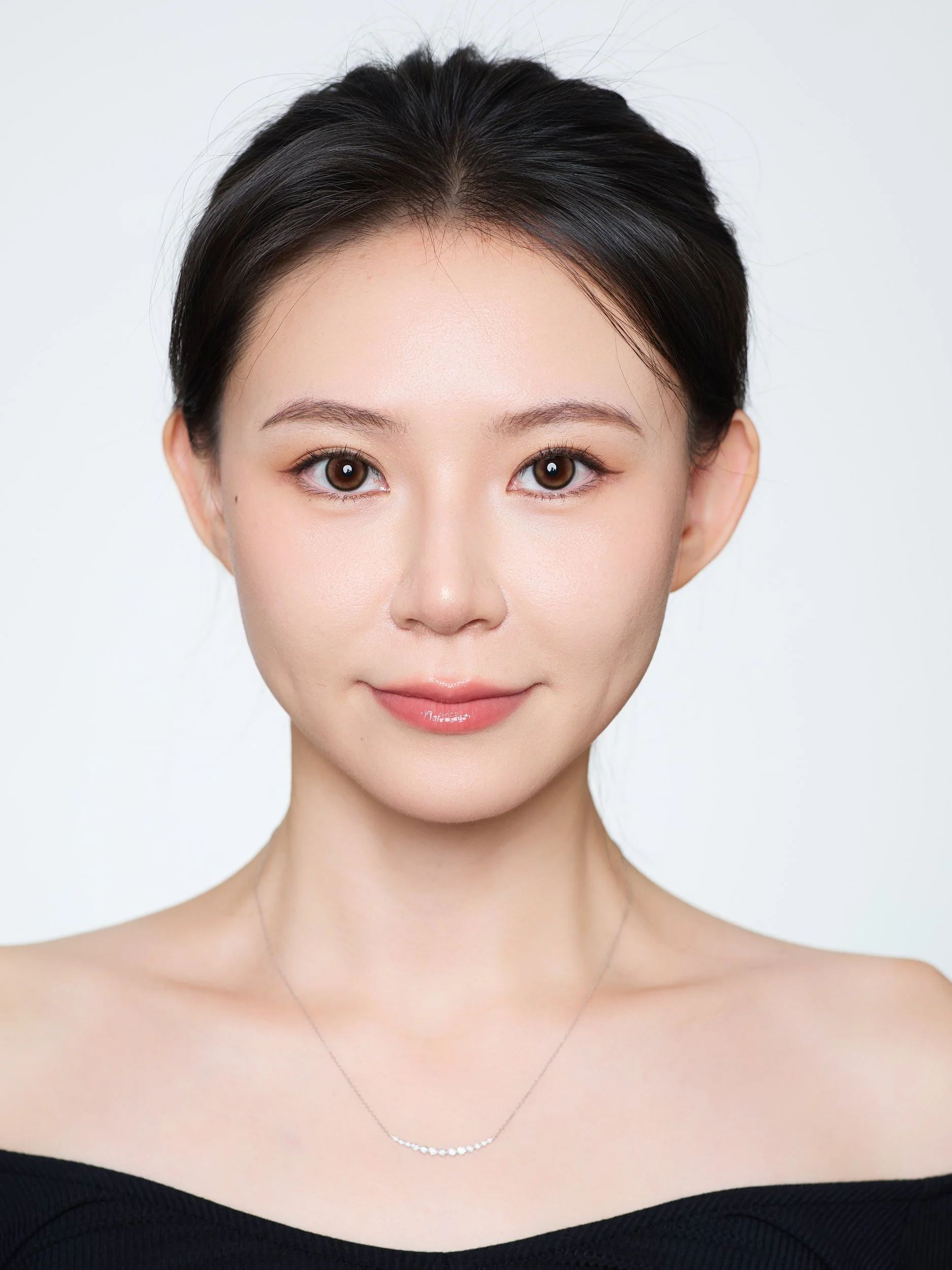 Front-facing ID-style headshot of a woman in an off-shoulder black top