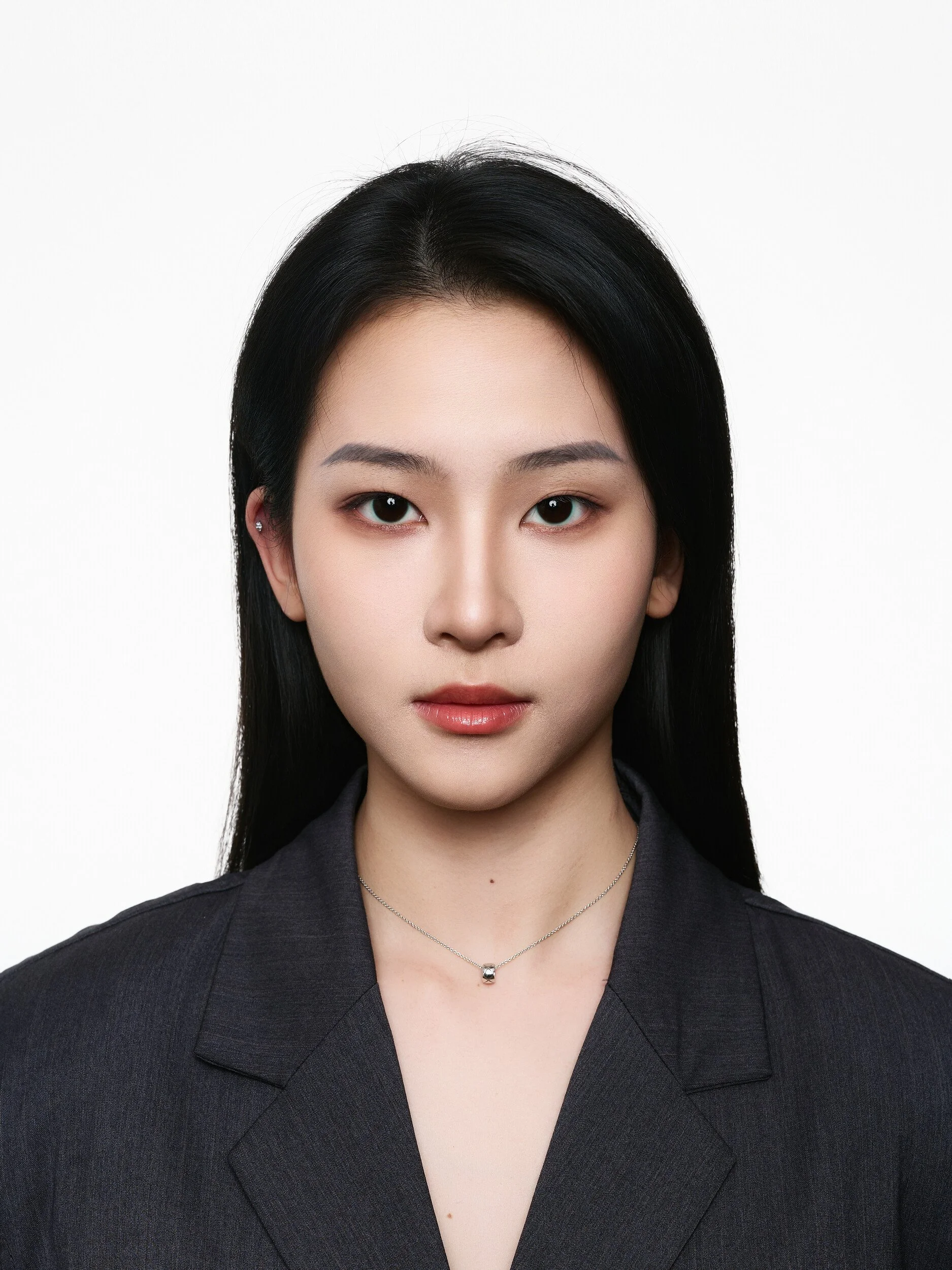 Front-facing ID-style headshot of a woman in a dark blazer on white