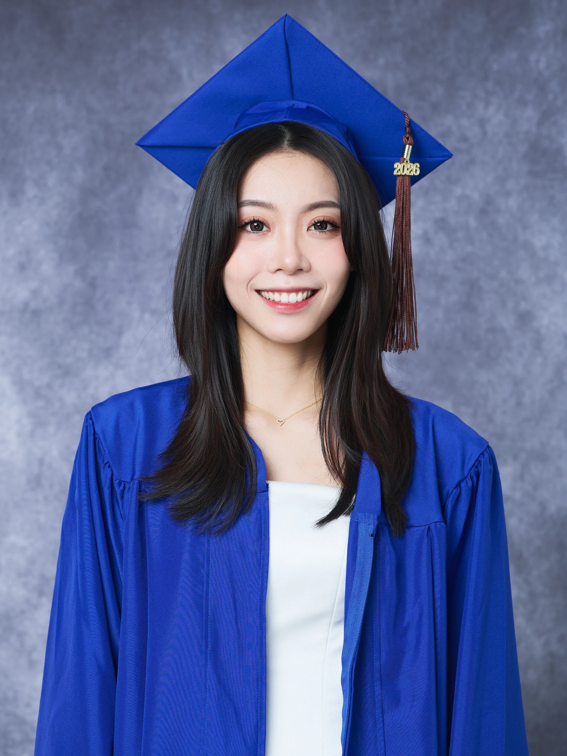 FIT graduation portrait of a smiling woman in a royal blue cap and gown