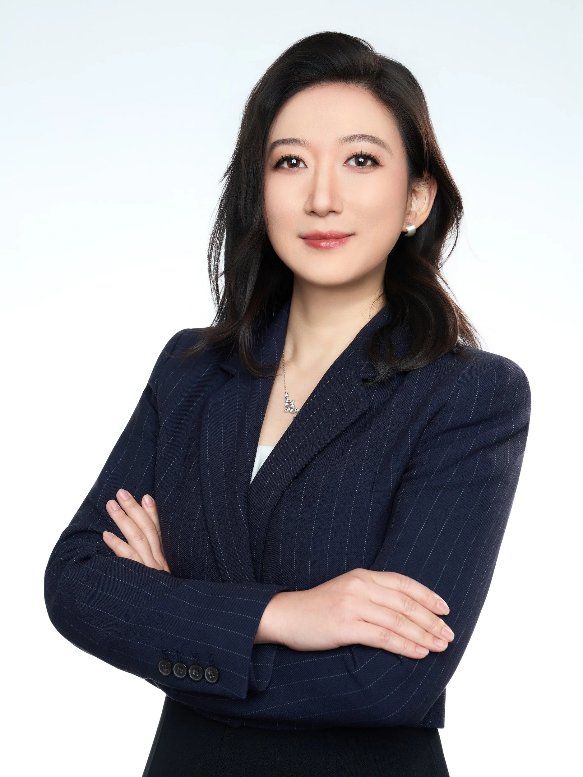 Professional headshot of a woman in a navy pinstripe blazer with arms crossed