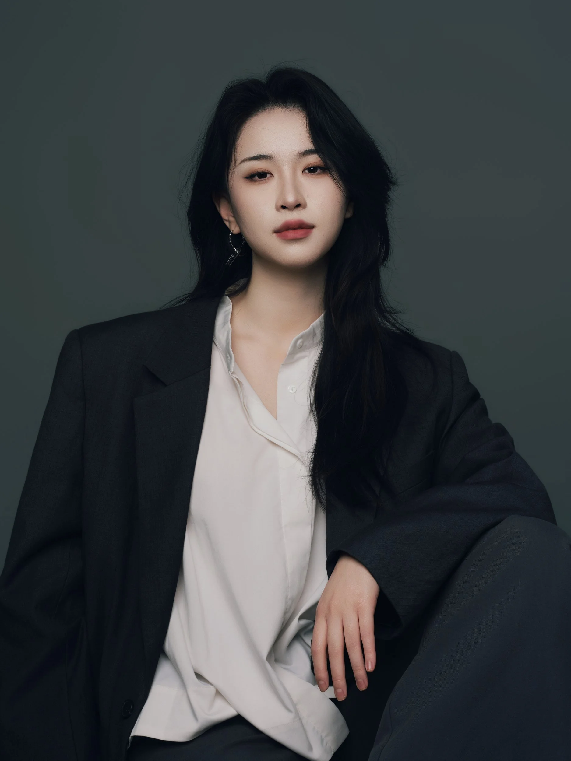 Seated studio portrait of a woman in an oversized black blazer