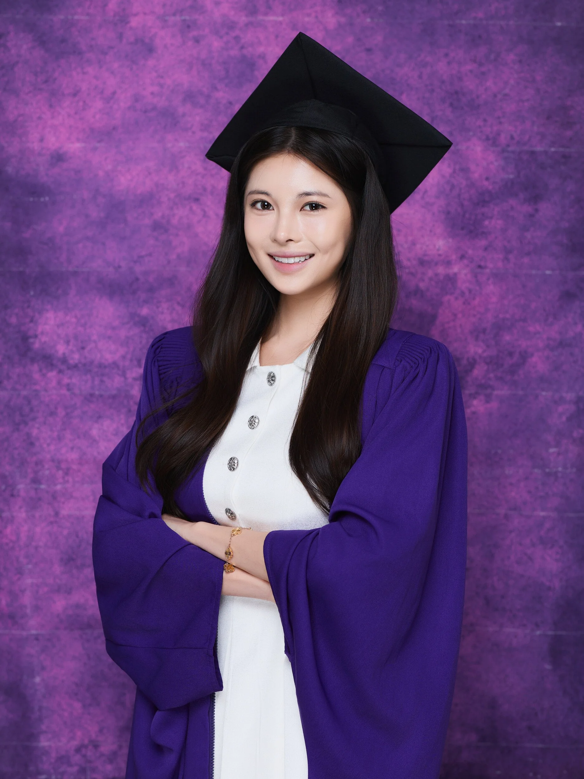 NYU graduation portrait of a smiling woman in a white dress with arms crossed