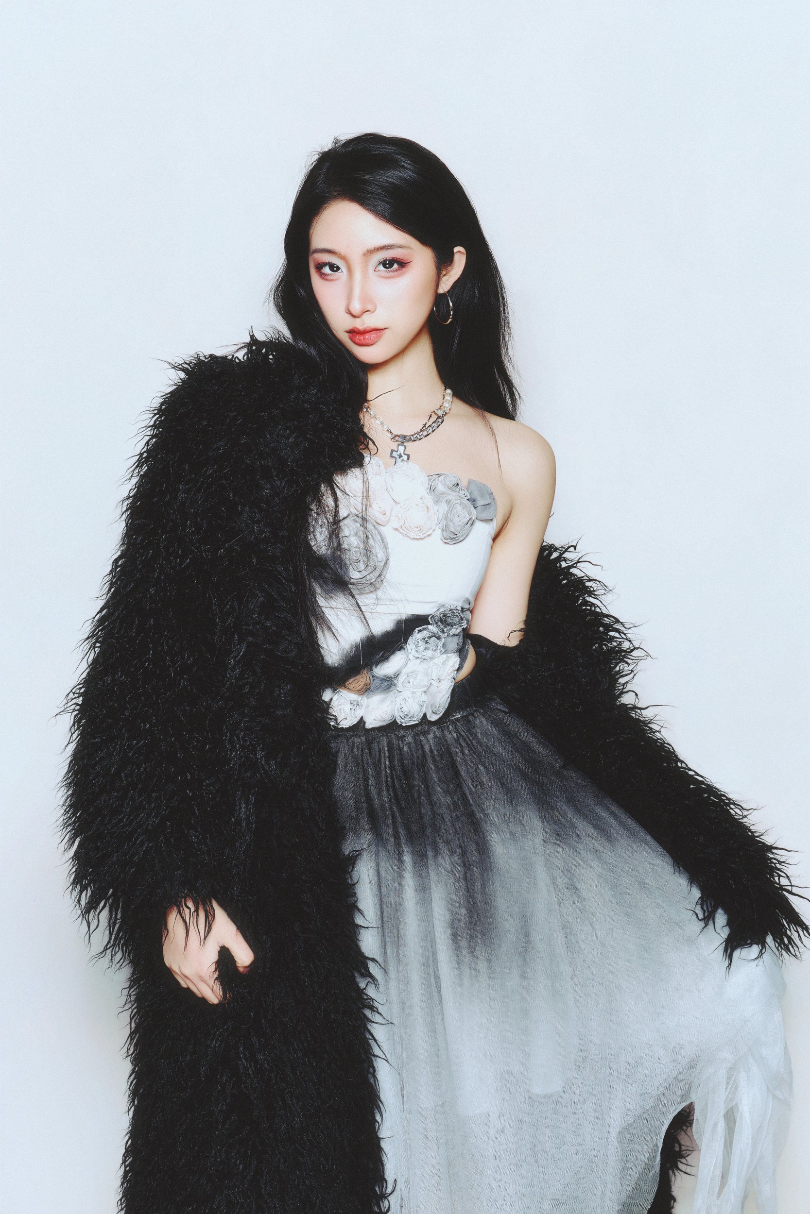 Studio portrait of a woman in a black faux fur jacket and grey dress