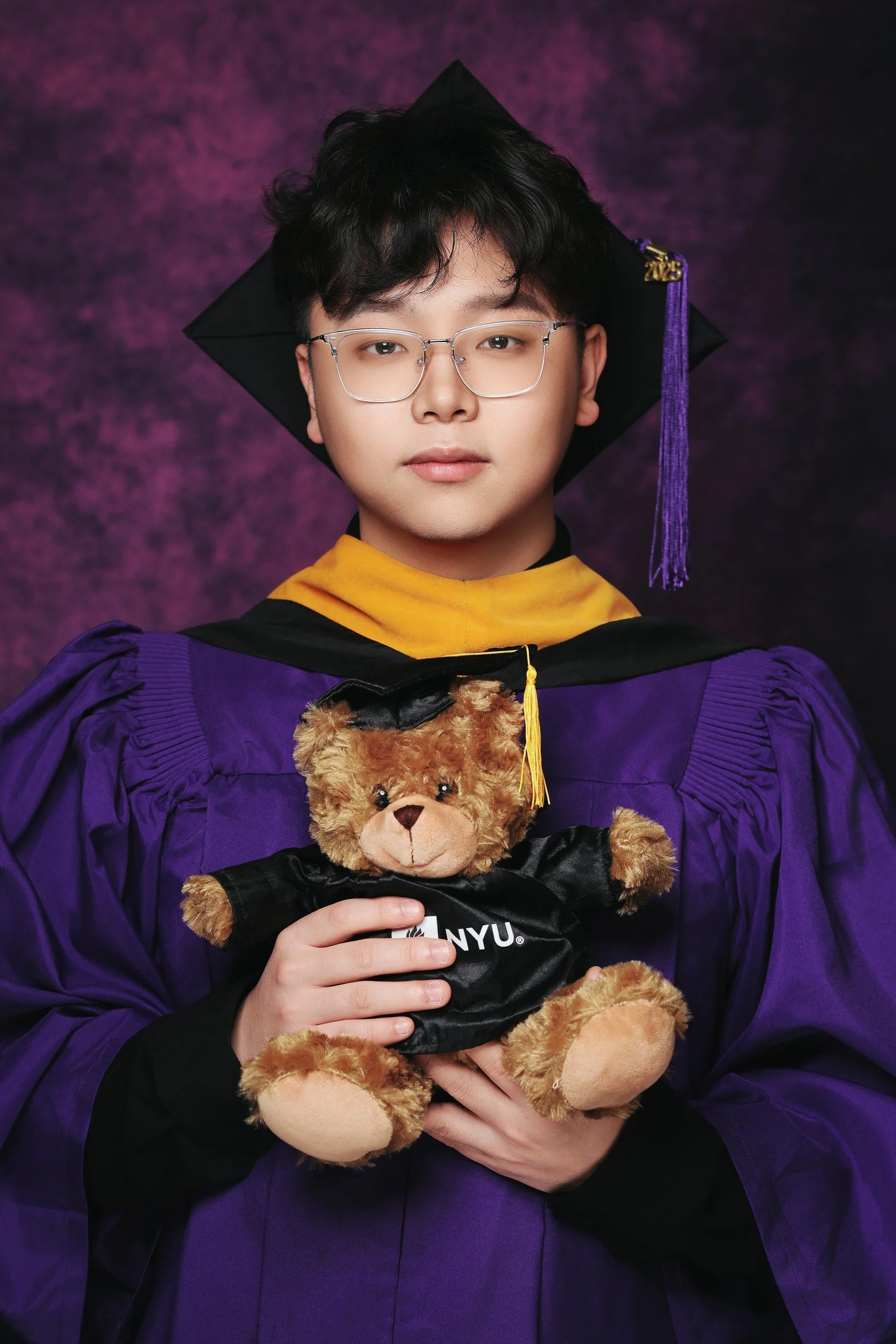 Graduation portrait of a graduate in cap and gown holding a teddy bear