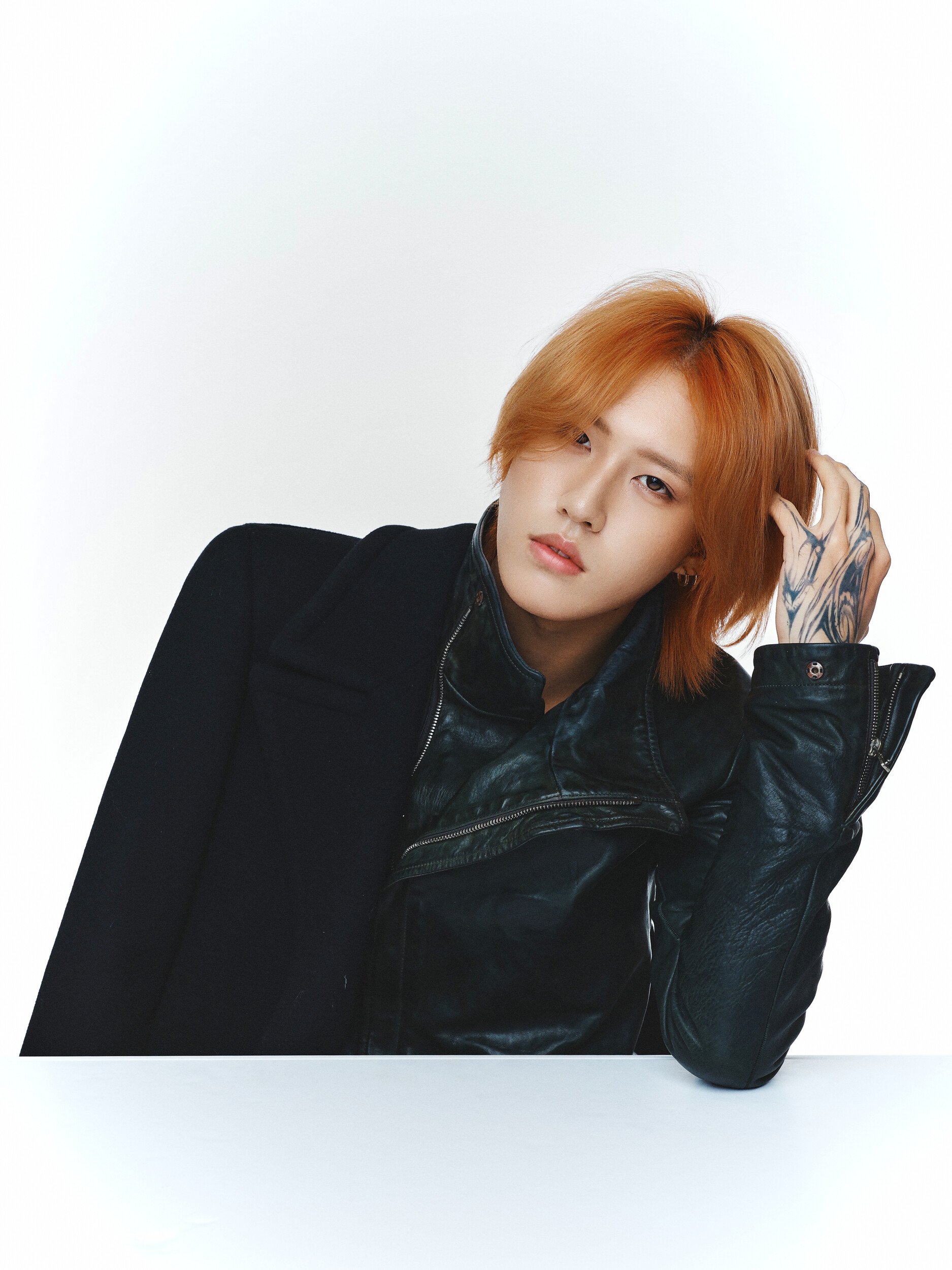 Studio portrait of a man with orange hair resting his head on his hand