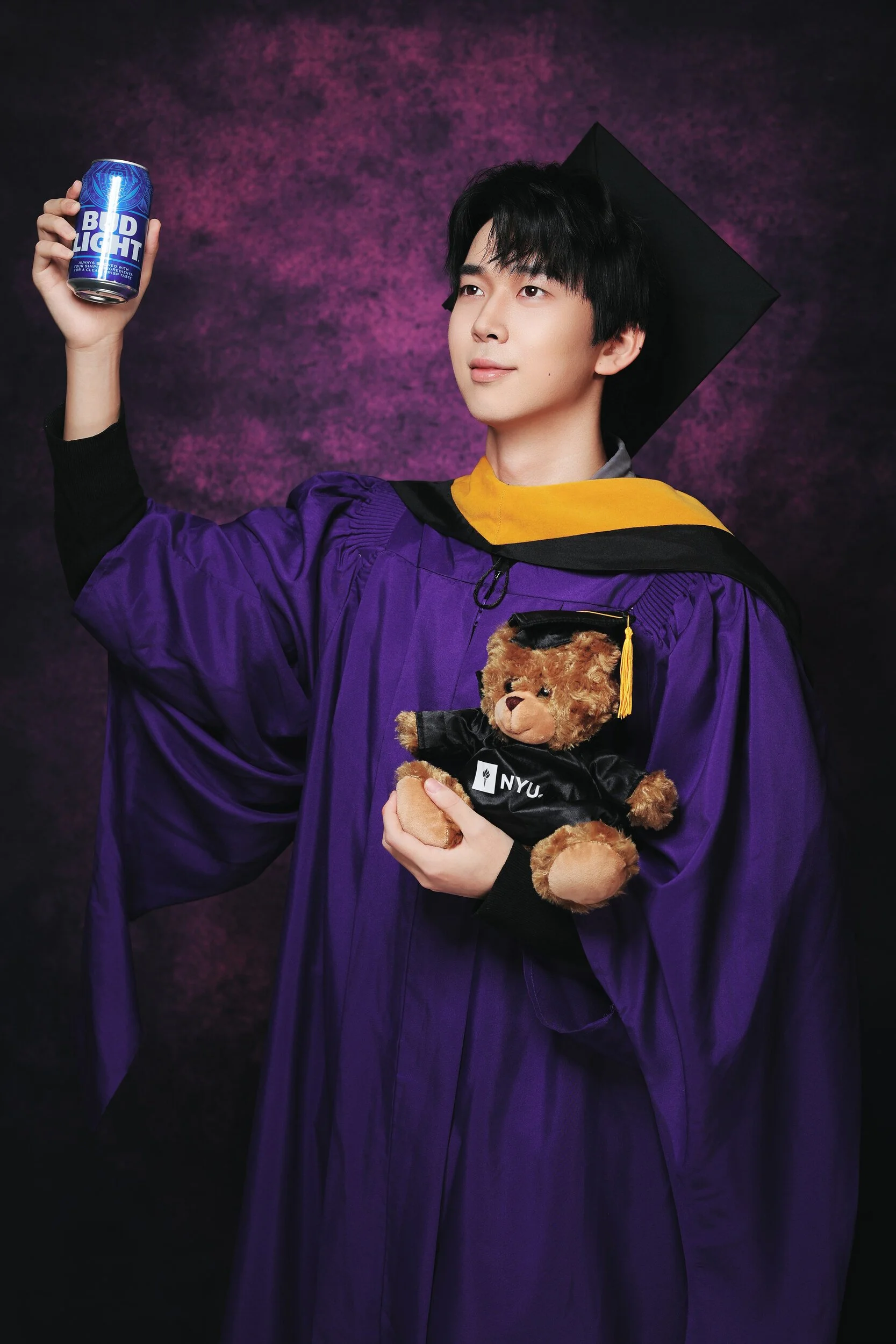 NYU Tandon graduation portrait of a young man raising a can while holding a teddy bear